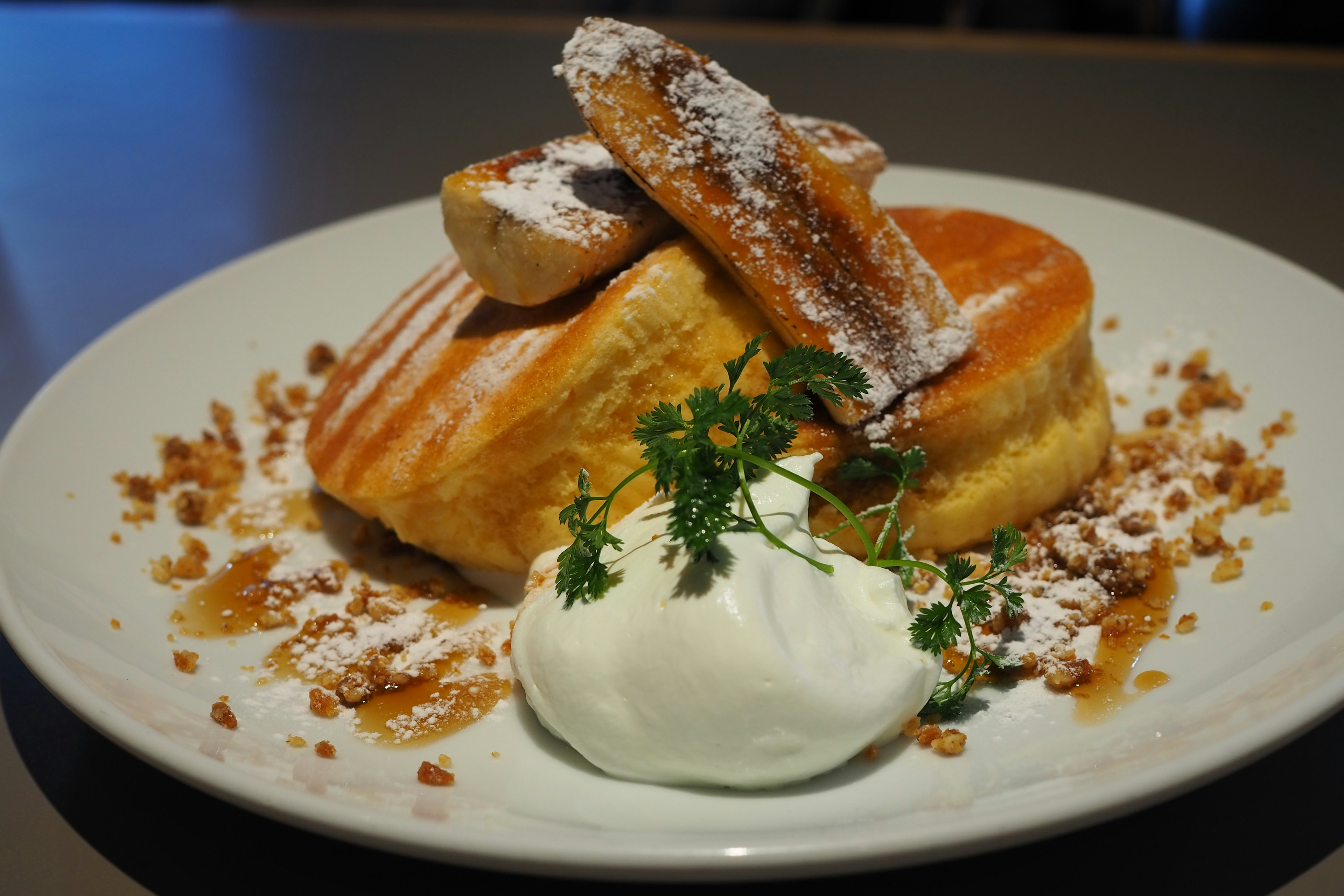 Fluffy pancakes topped with whipped cream and garnished with herbs