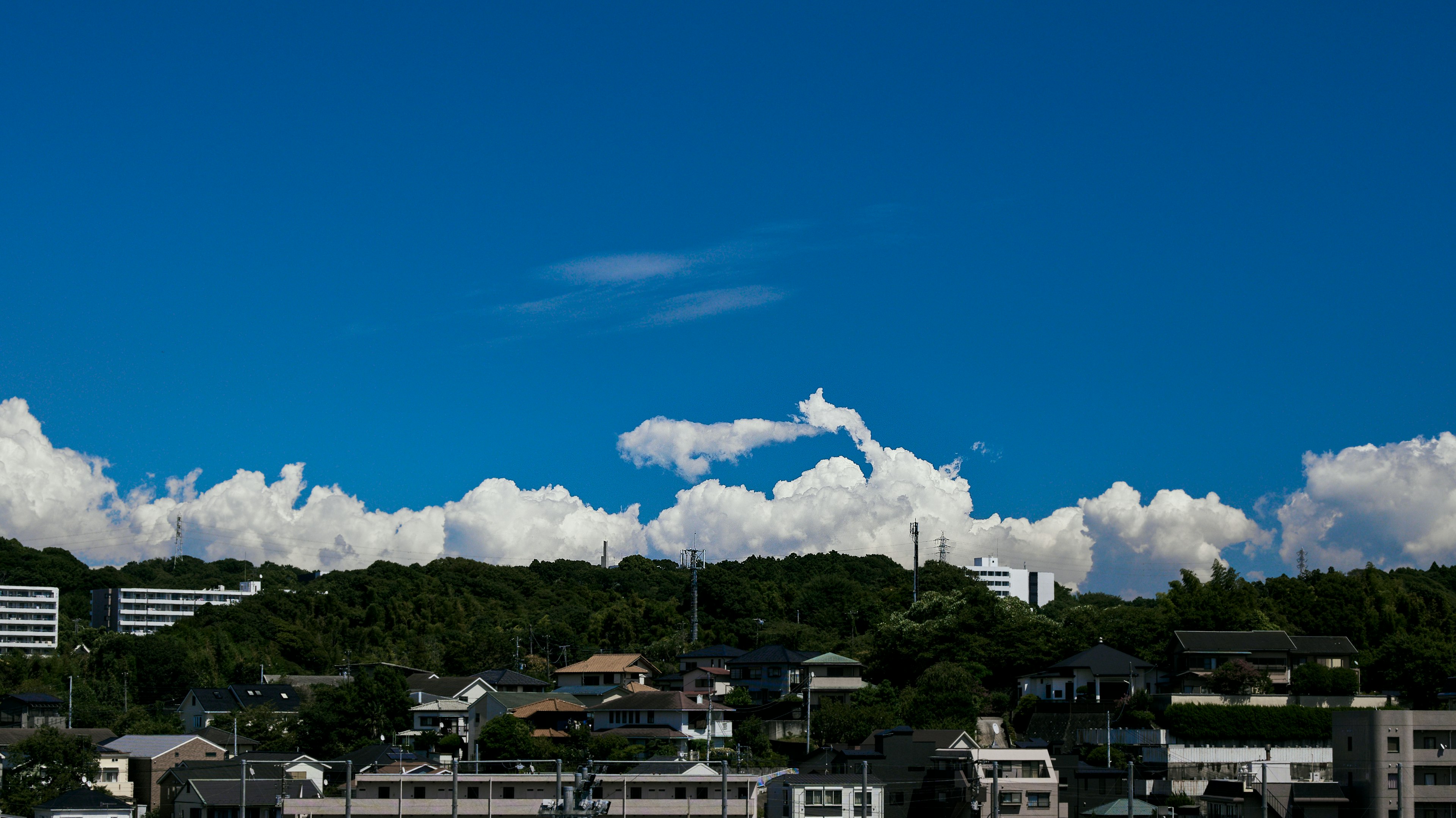 青空と白い雲を背景にした住宅街の風景