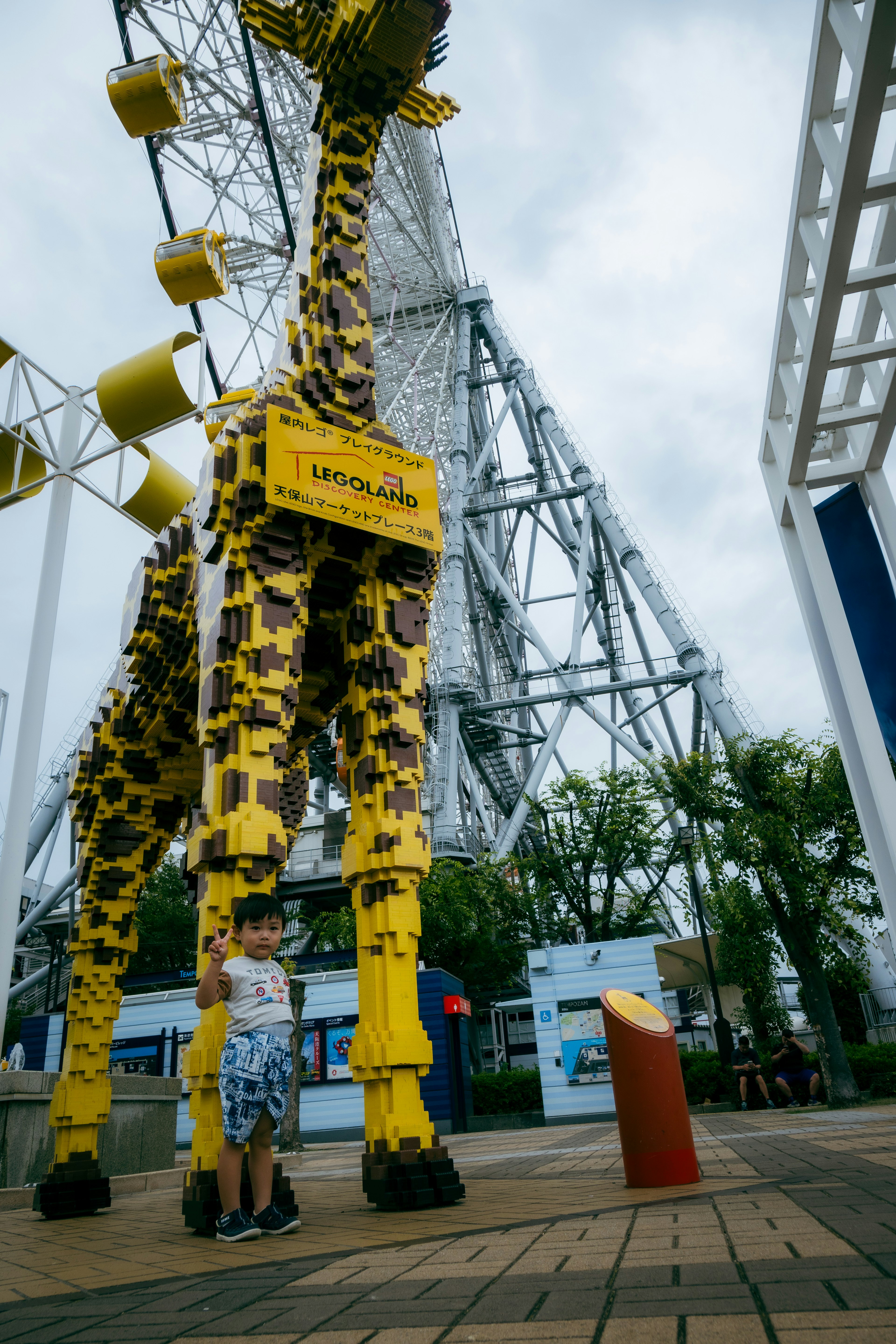 Enfants interagissant avec une grande sculpture de girafe jaune près d'une grande roue