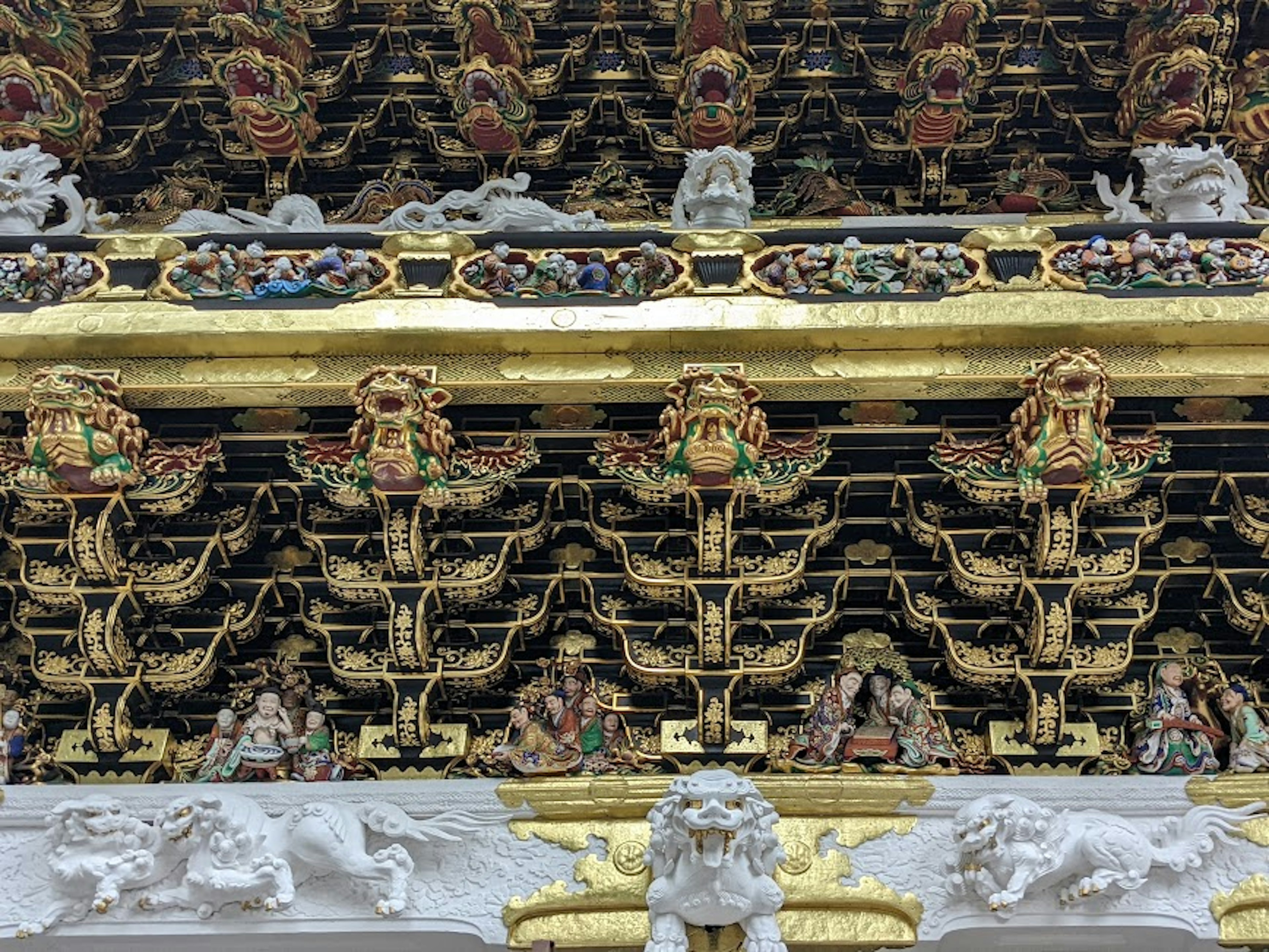 Section de toit de temple avec des décorations ornées présentant des sculptures dorées et des statues de lions