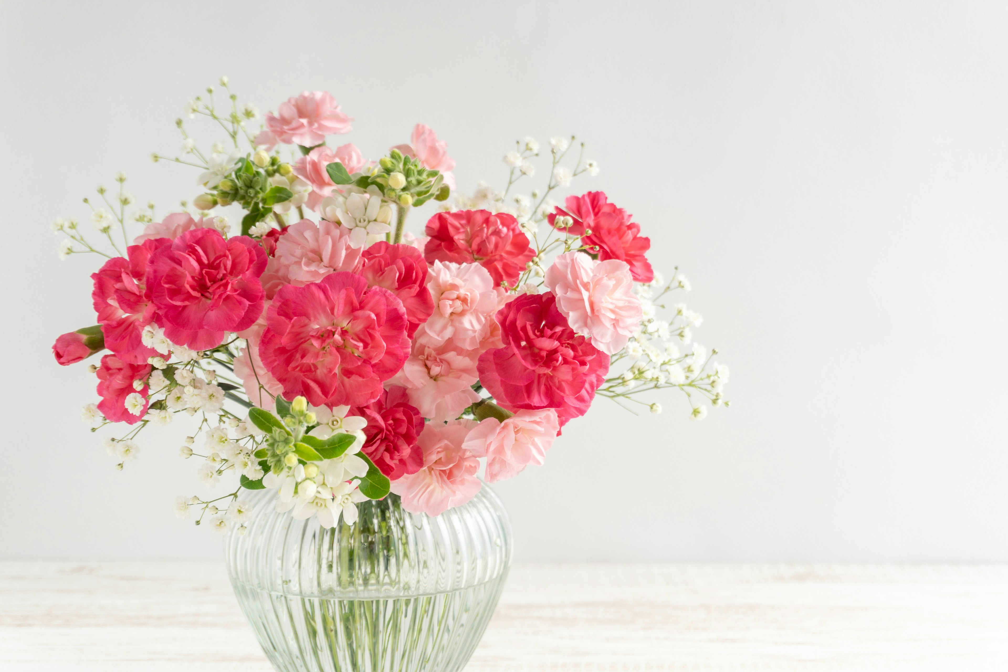 A bouquet of pink and white carnations arranged in a glass vase