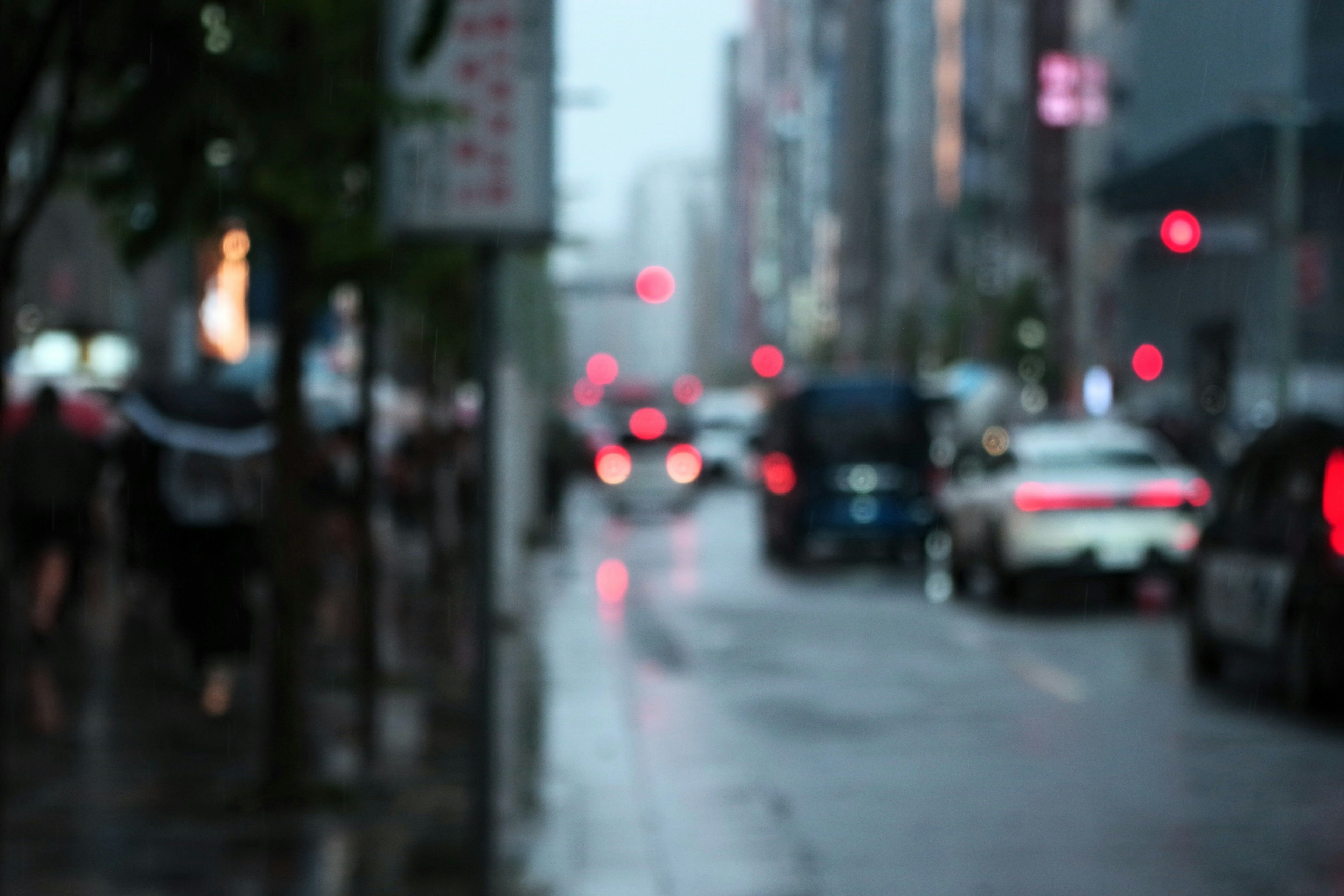 雨の中でぼやけた街の風景 車と人々が行き交う