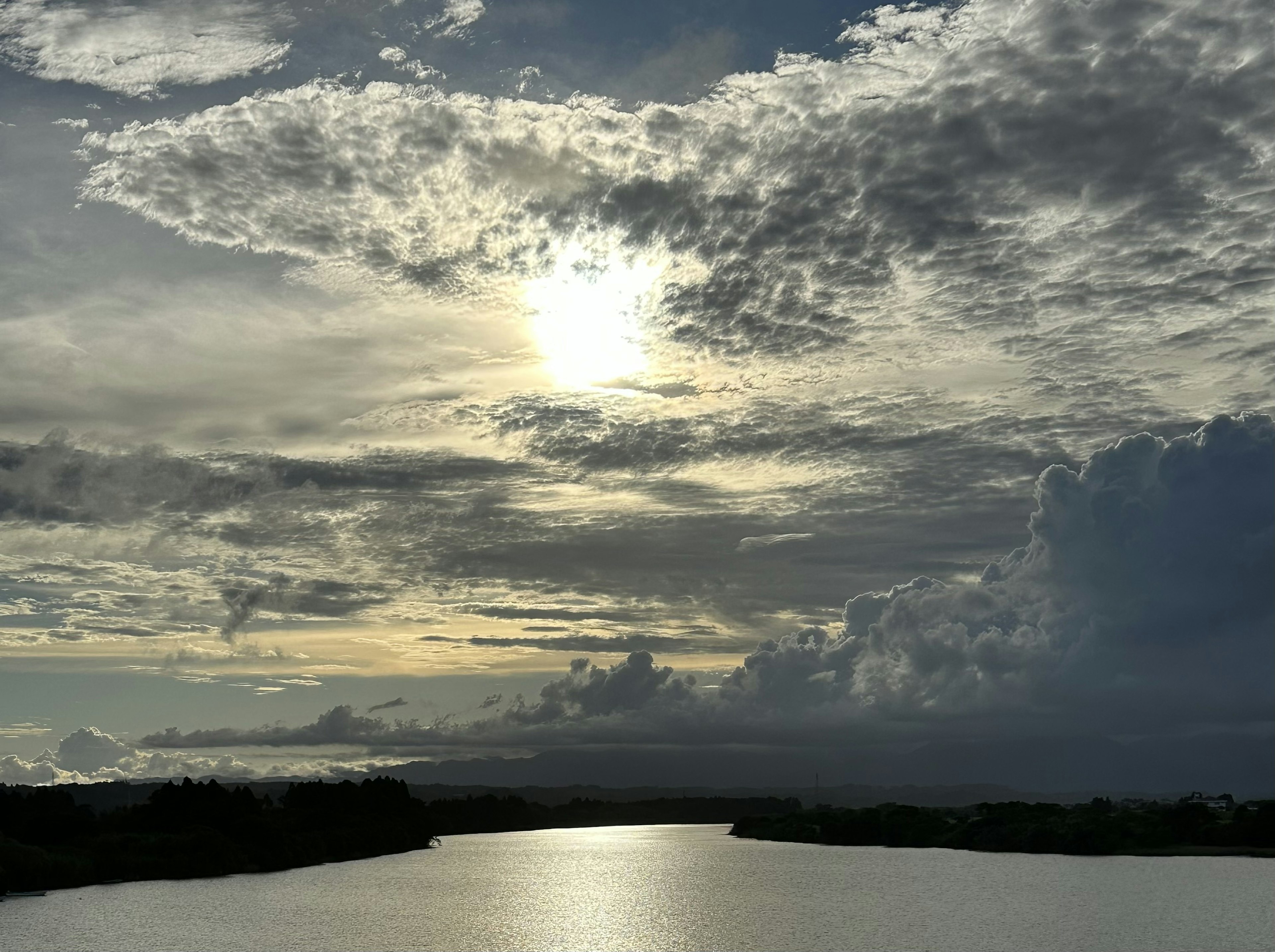 Ein ruhiger Fluss mit Wolken und Sonnenlicht, das sich auf dem Wasser spiegelt