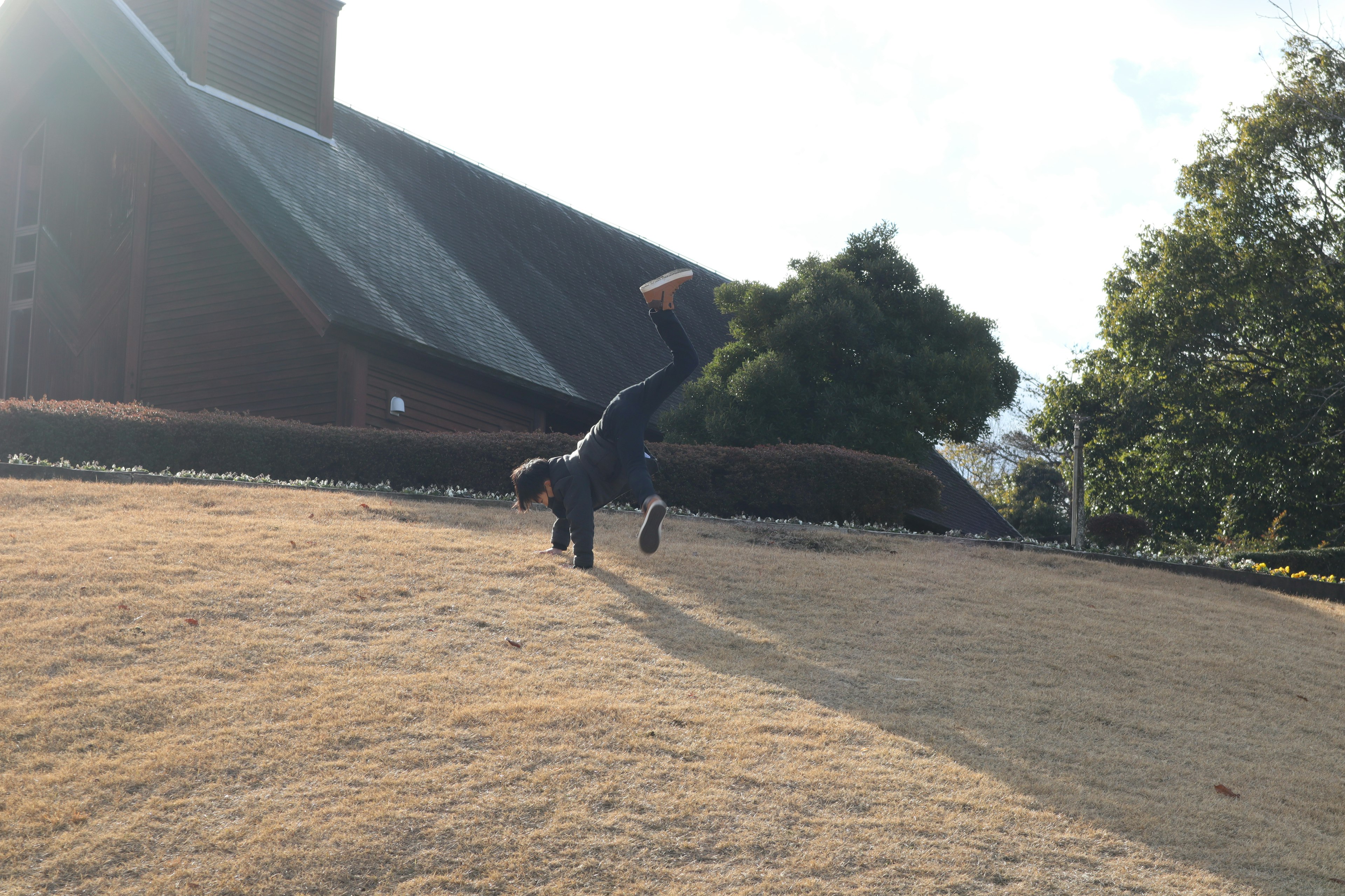 Eine Person, die auf dem Gras einen Handstand macht, mit einem Kirchengebäude im Hintergrund