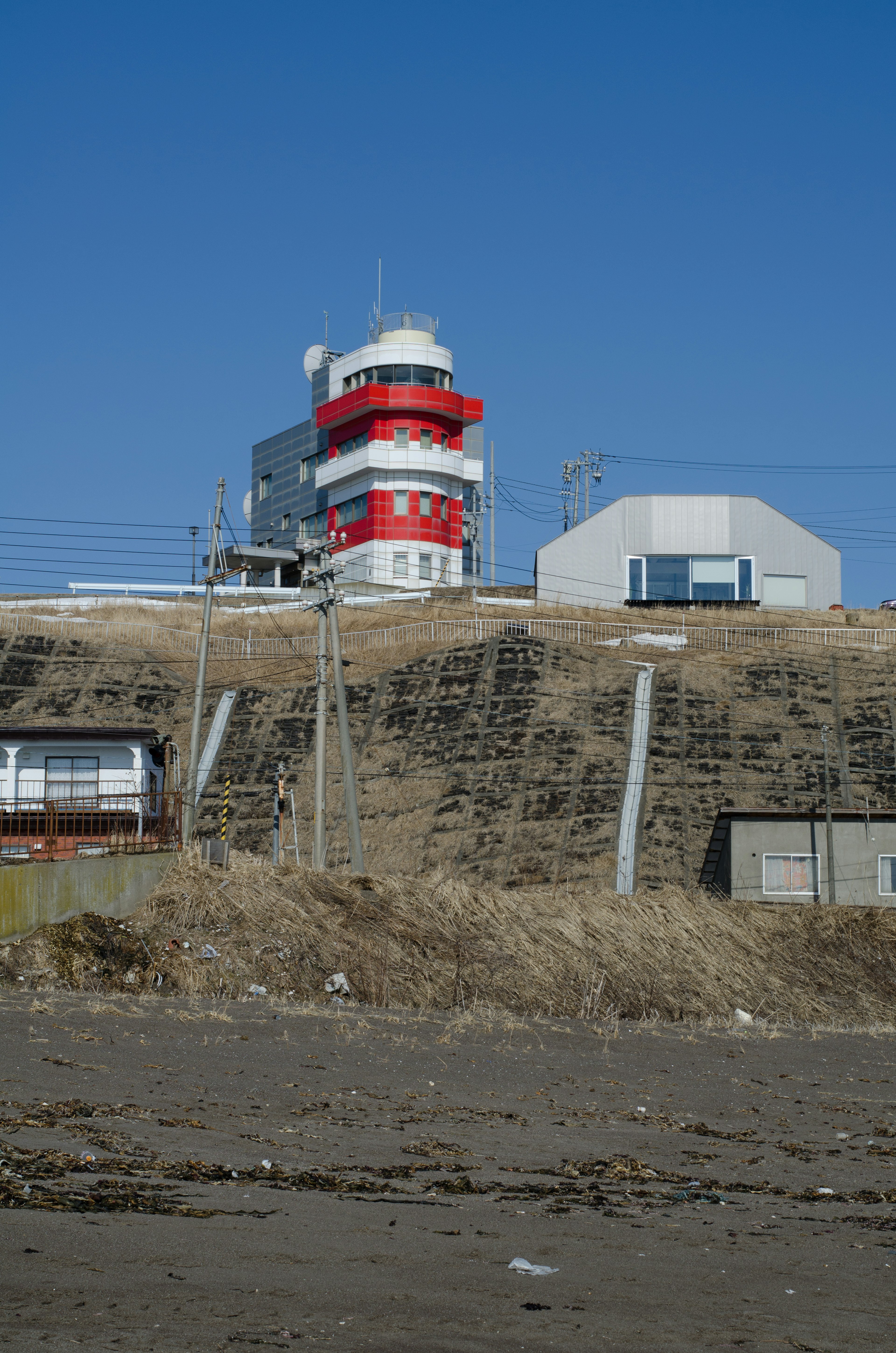 Scène côtière avec un bâtiment rouge et blanc sous un ciel bleu