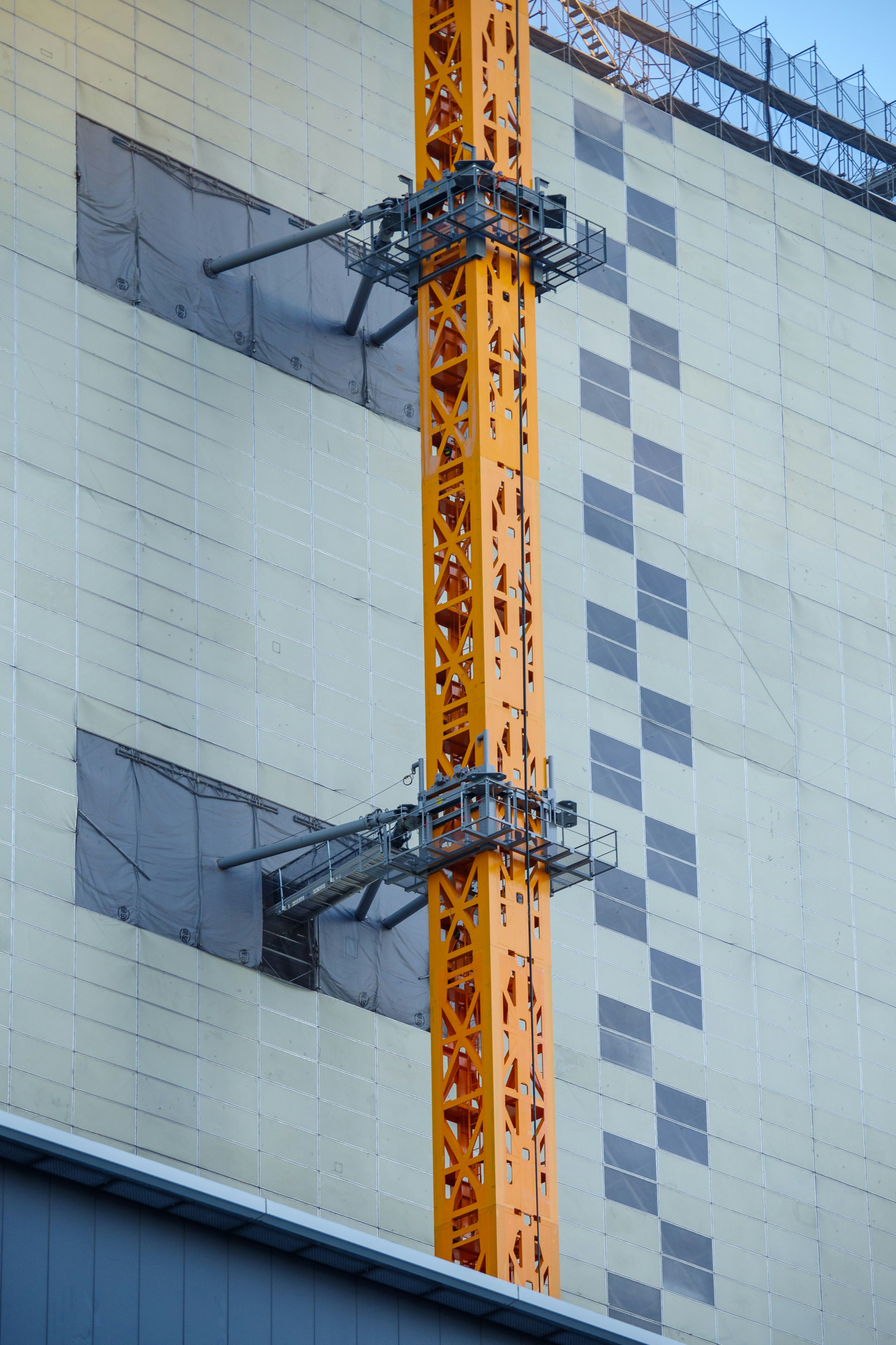 Imagen que muestra una grúa naranja y parte de la fachada de un edificio