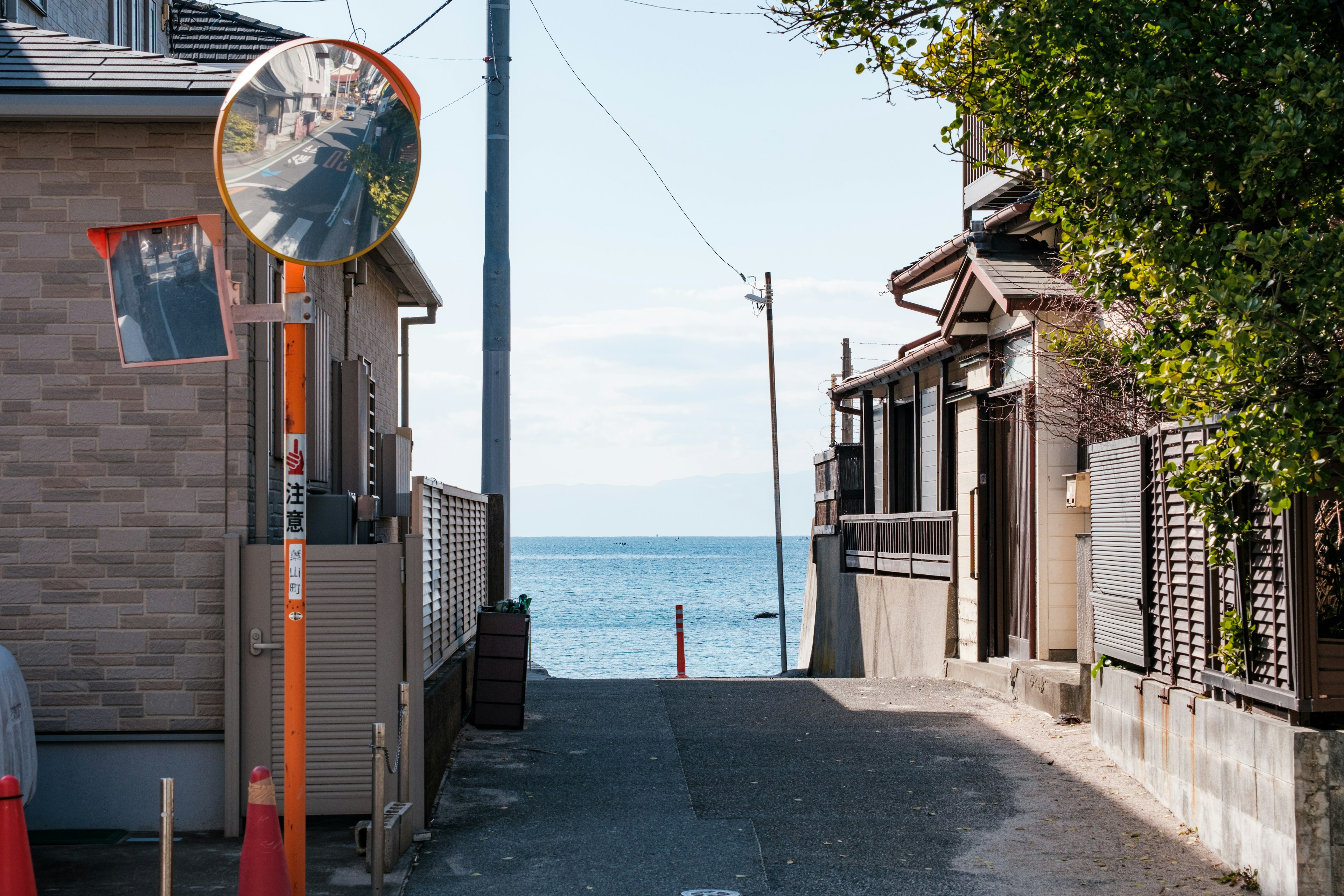 Vista di una stretta strada che porta al mare con uno specchio e case