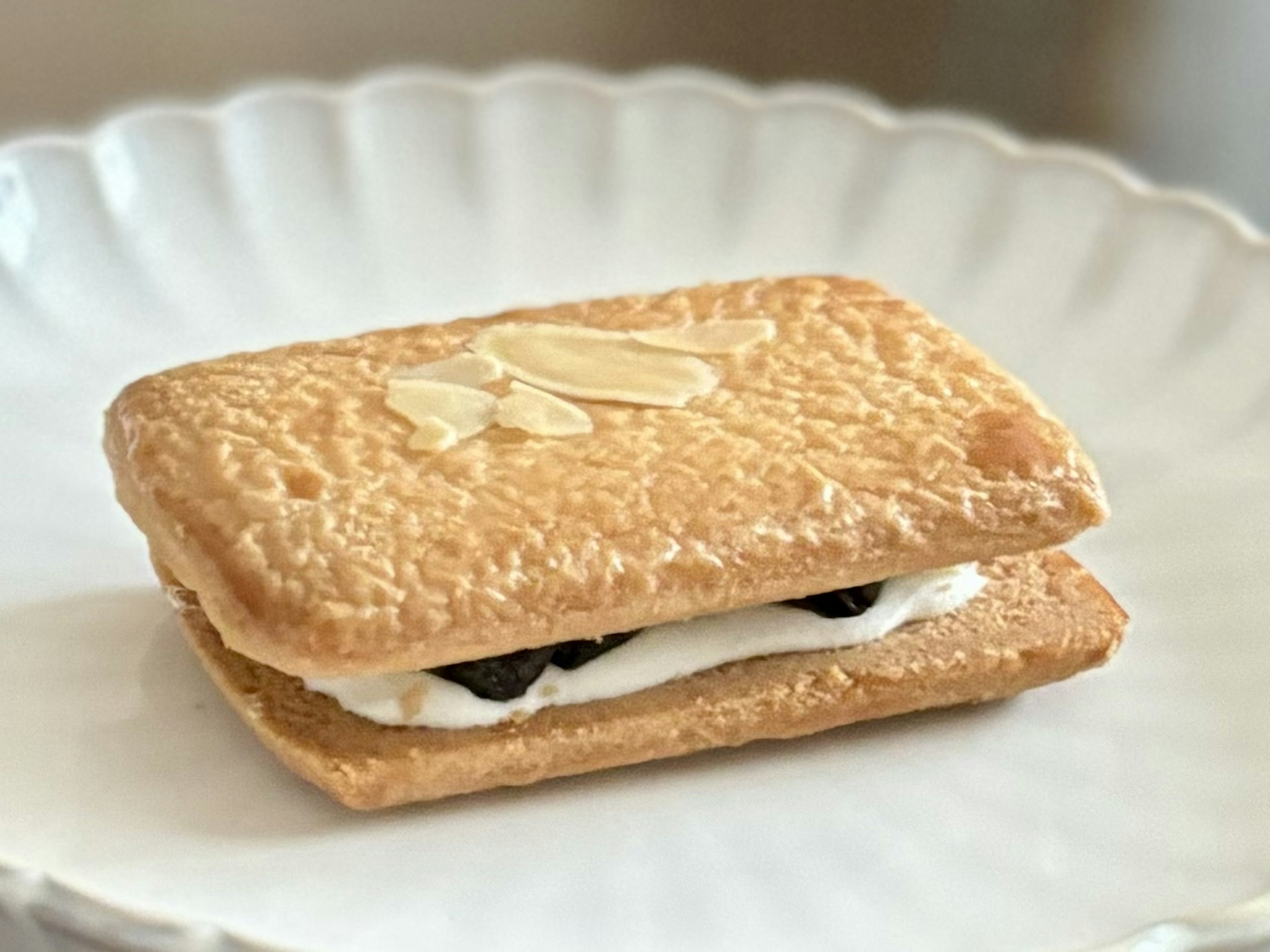 A thin biscuit filled with cream and dark bits