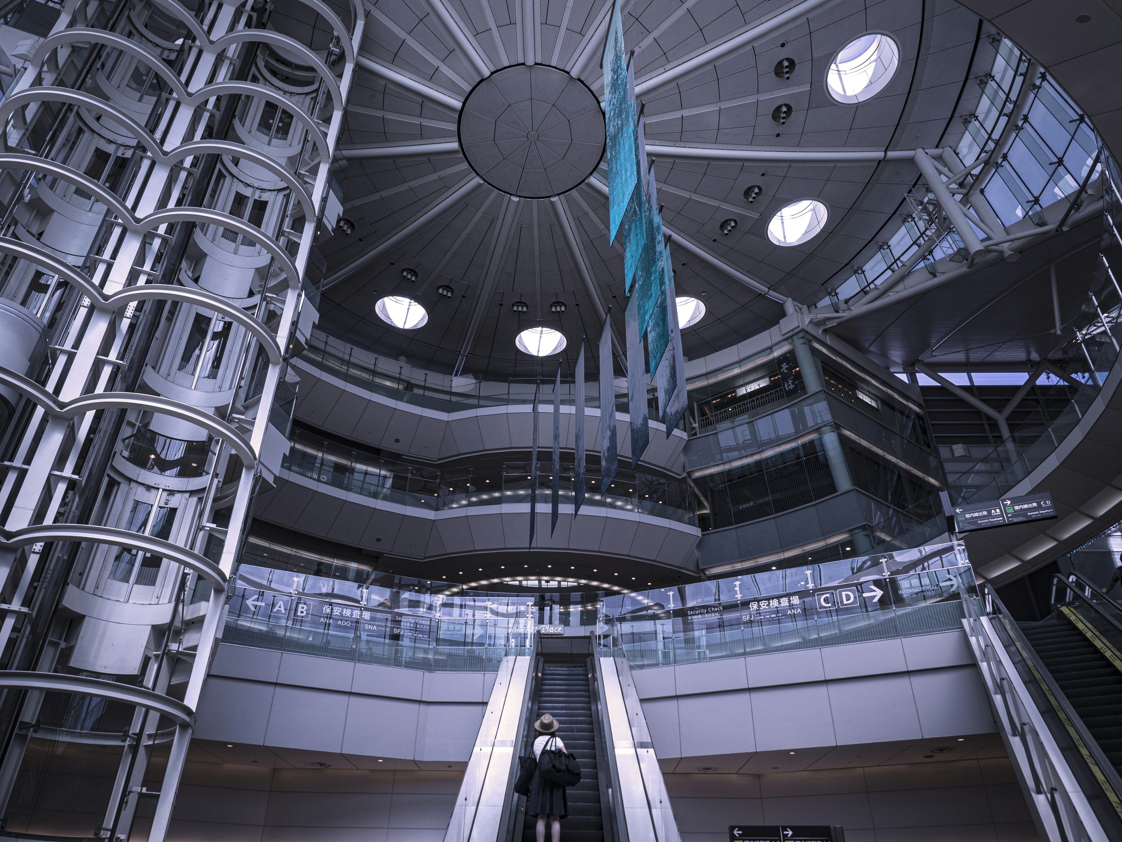 Interior view of a modern building with high ceiling round windows and blue banners stylish escalator