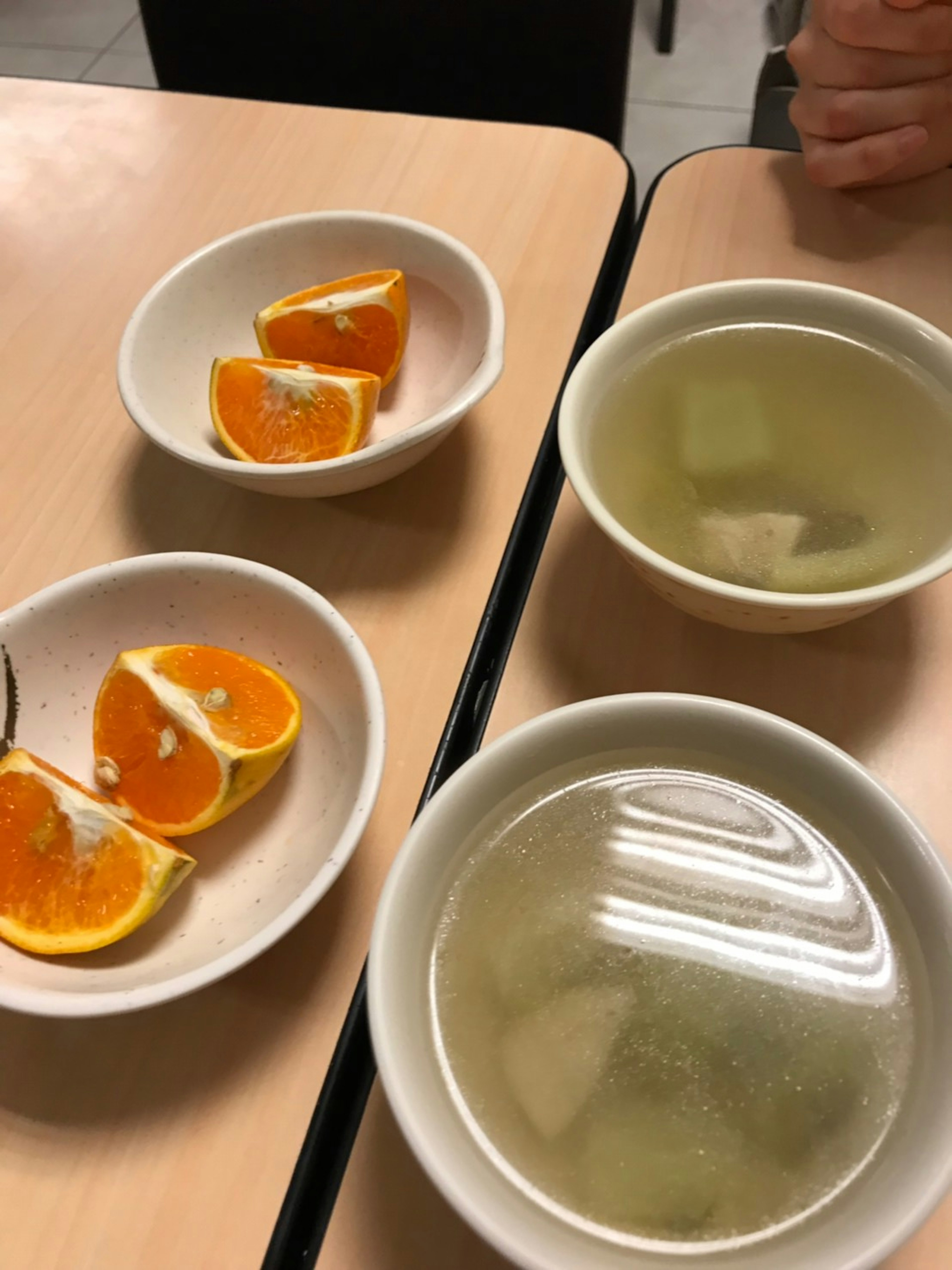 Sliced oranges and clear soup bowls on a table