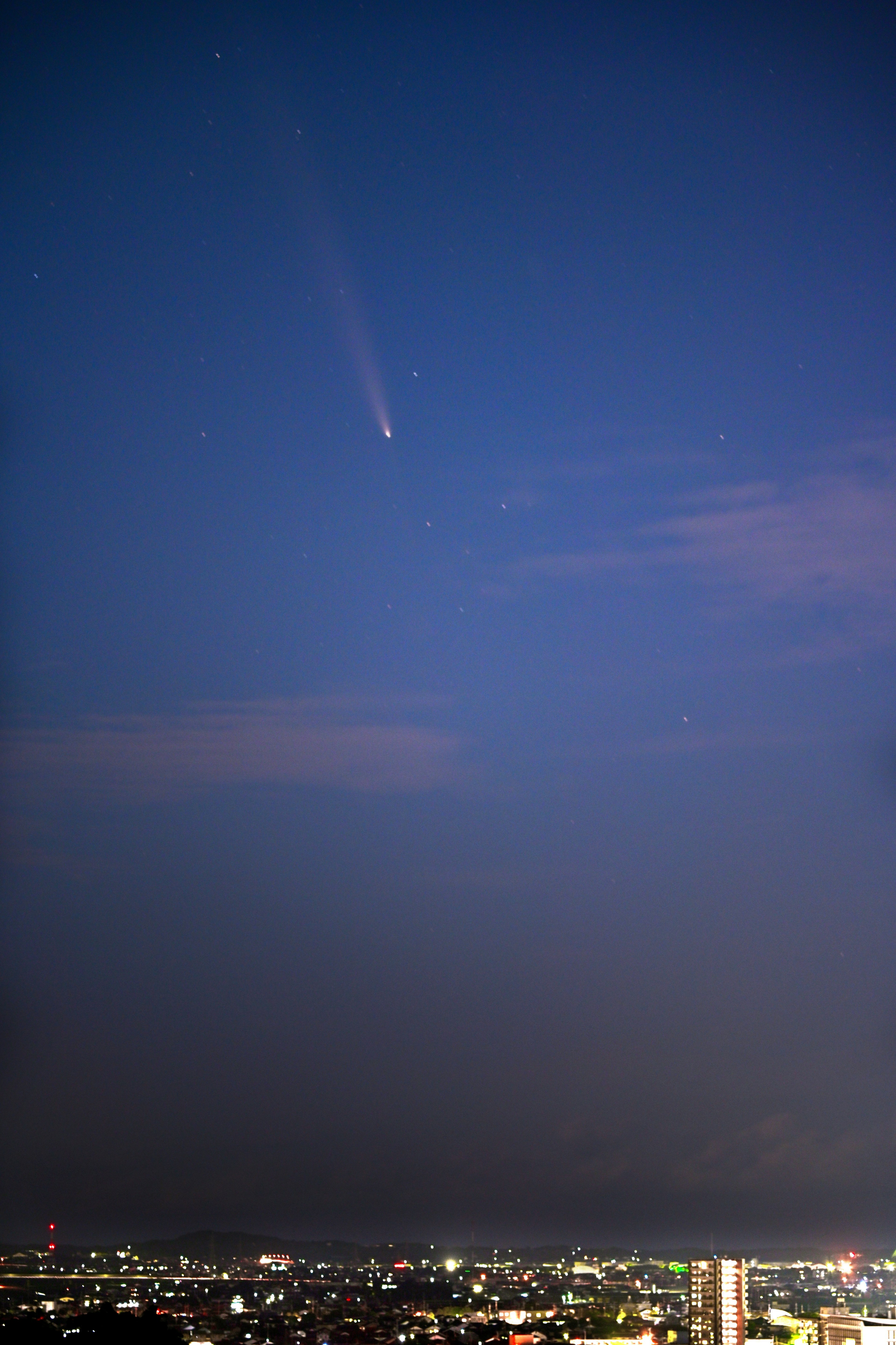 Comet shining in the night sky over a city skyline