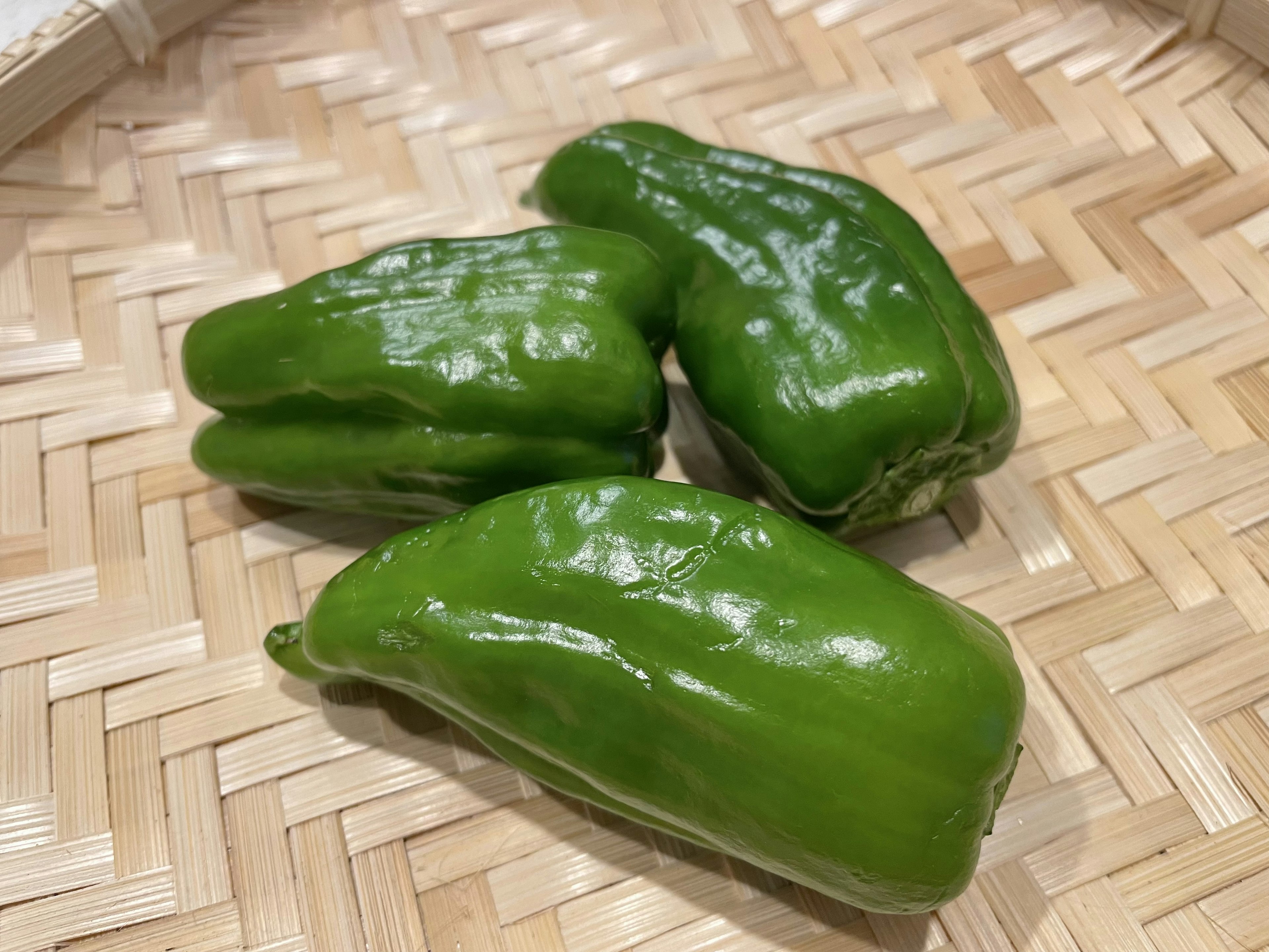 Fresh green bell peppers placed in a woven basket