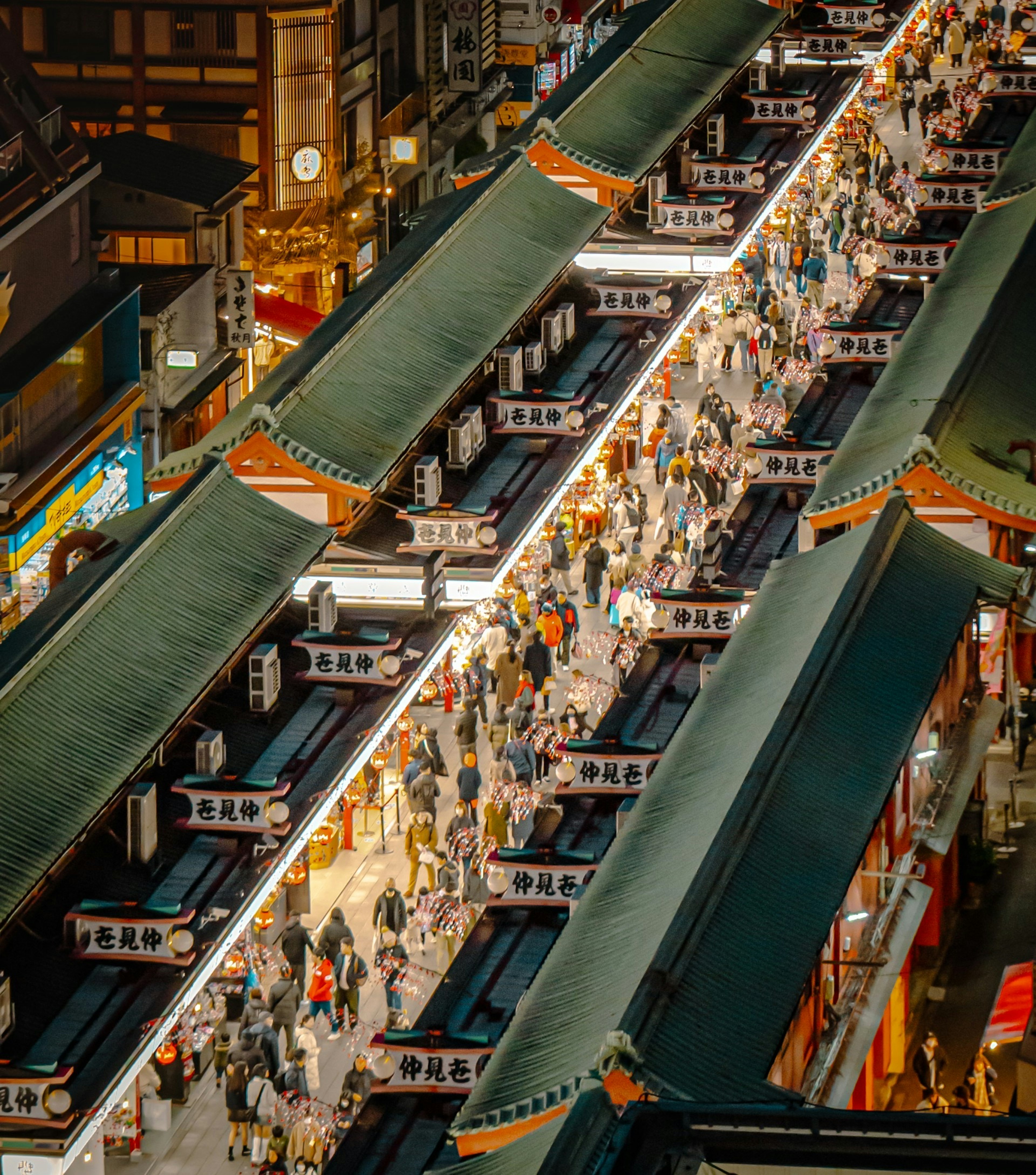 Aerial view of a bustling shopping street with many people walking under covered roofs