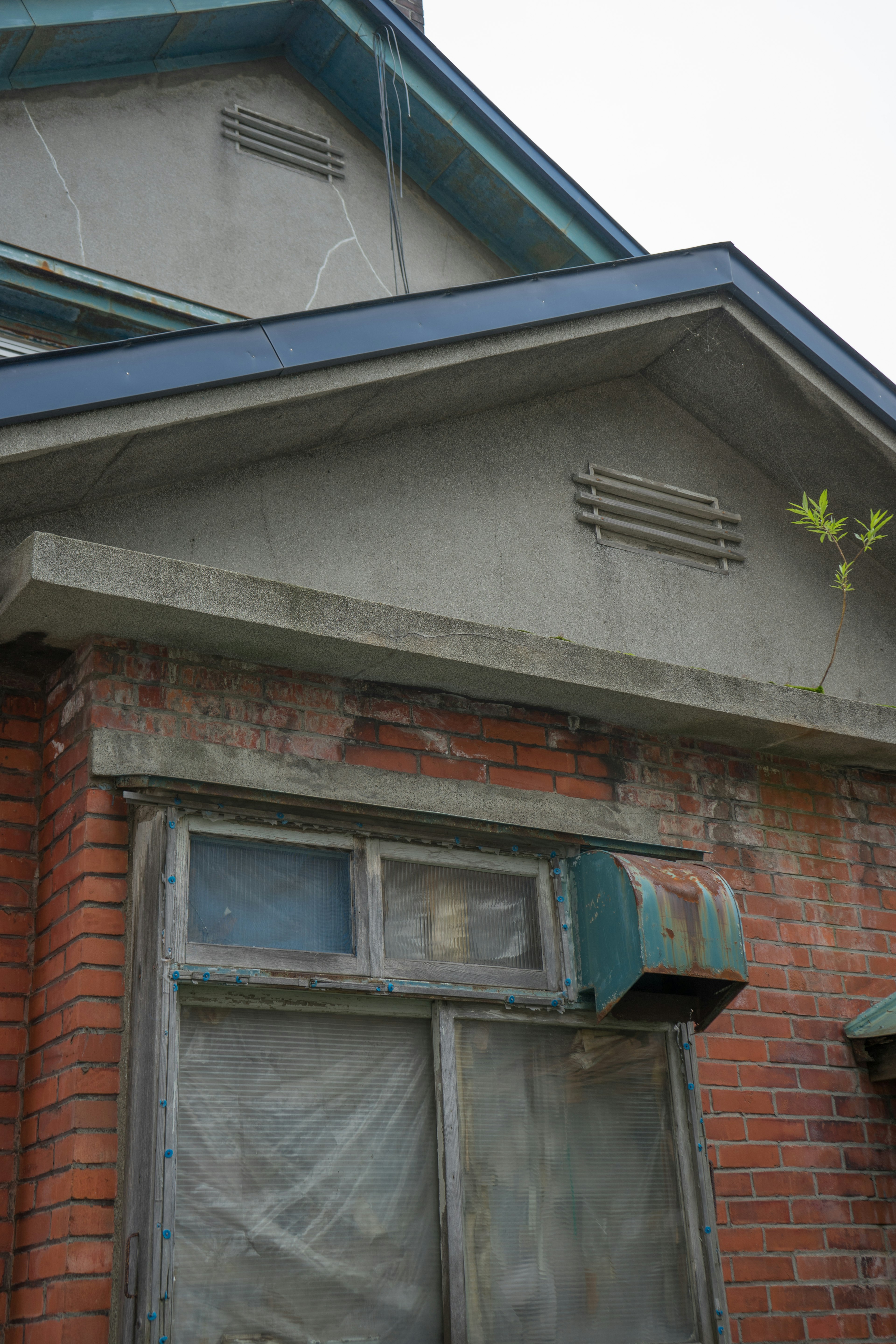 Eksterior rumah tua dengan dinding bata dan jendela kayu, cat atap yang mengelupas