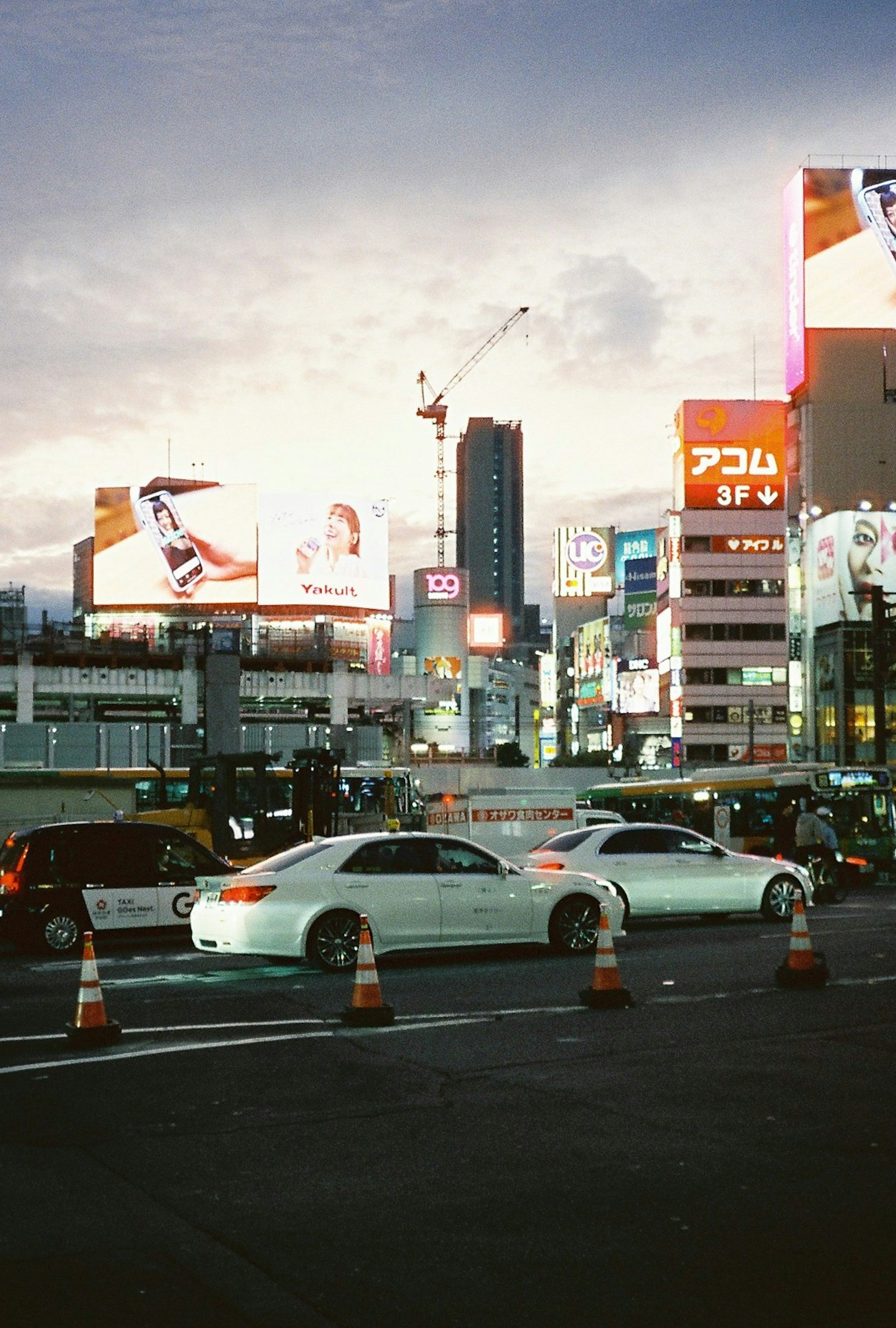 Traffic at a city intersection with bright billboards and buildings