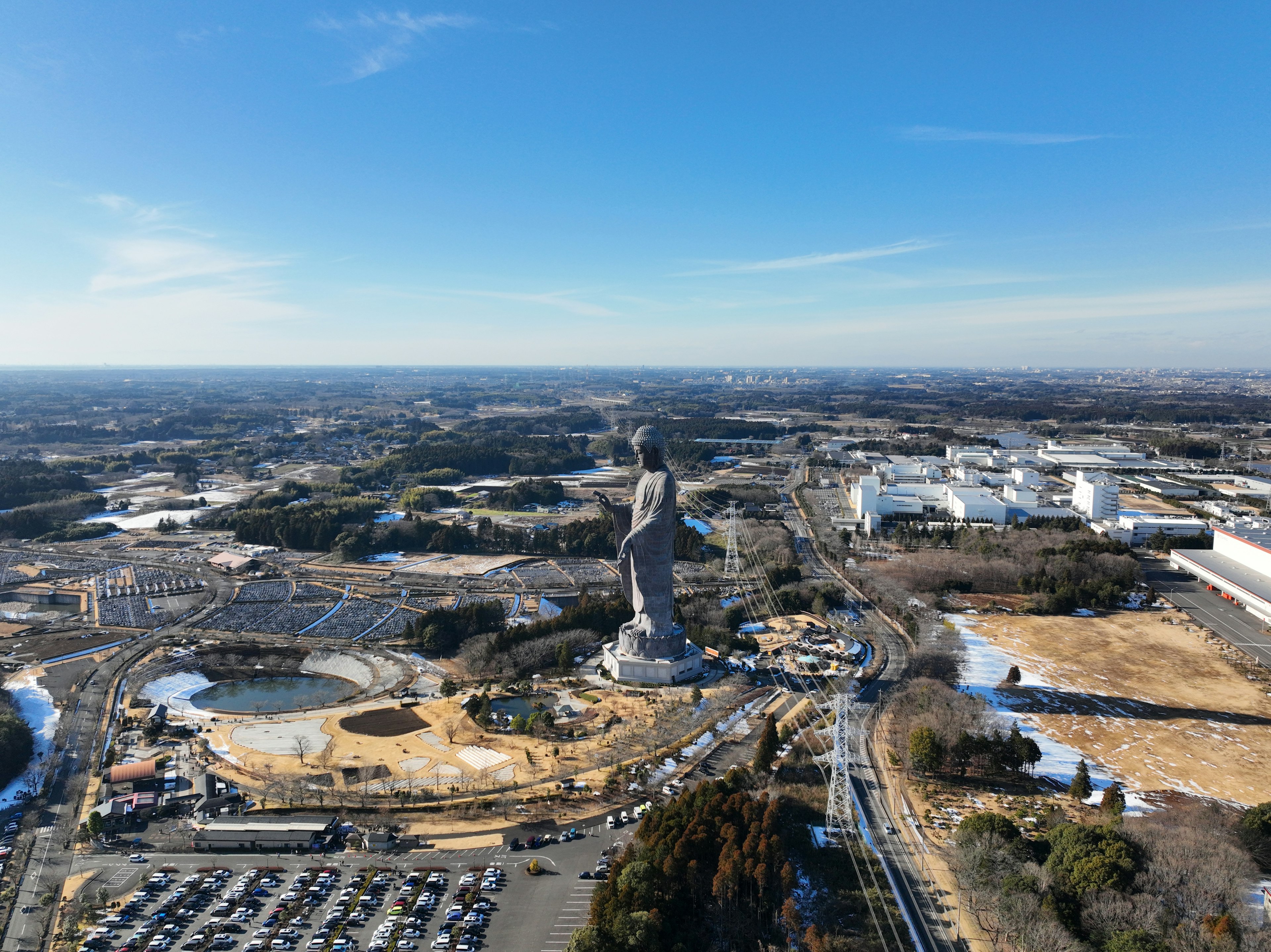 A vast landscape featuring a towering statue under a clear blue sky