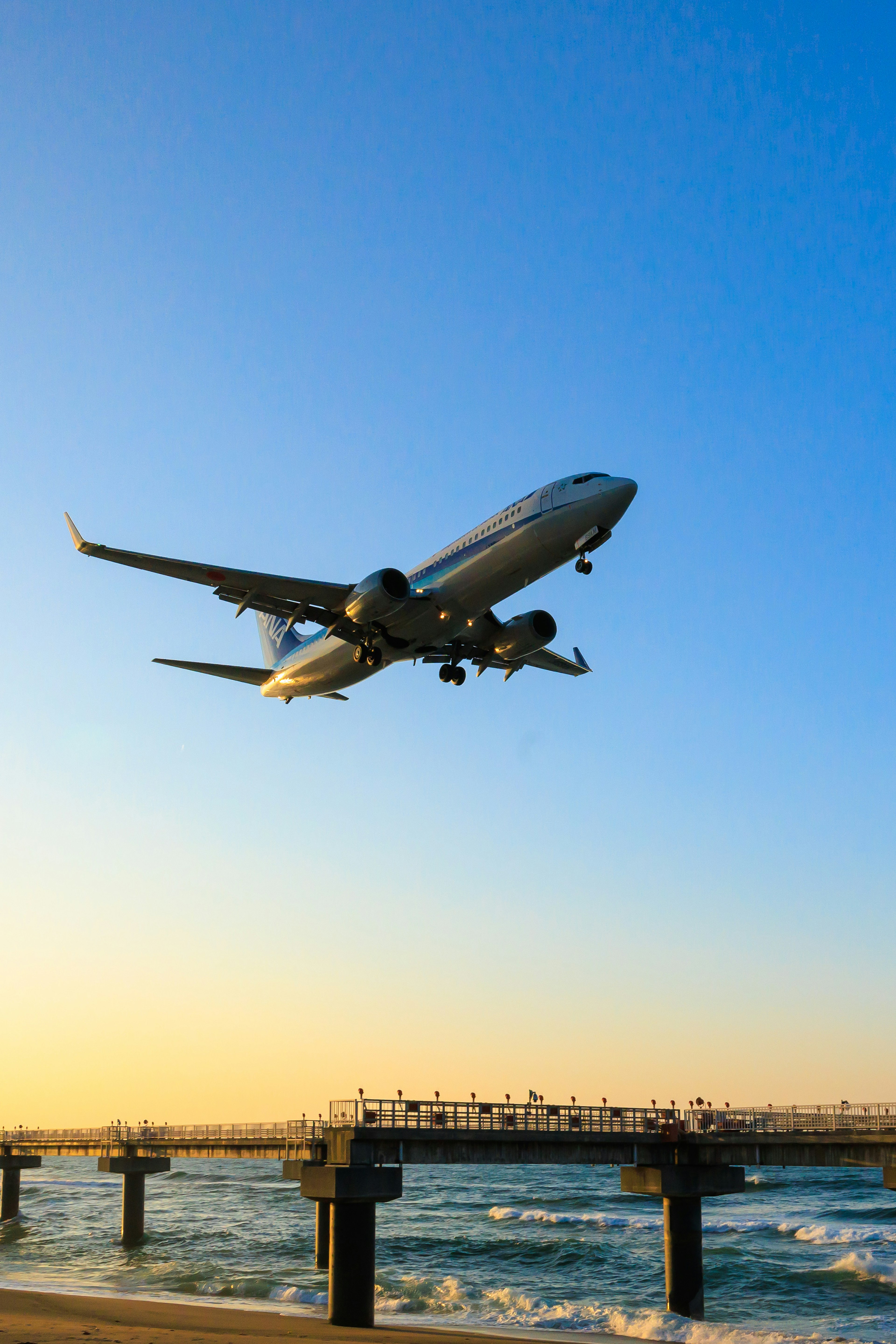 海の上を飛ぶ飛行機と夕日