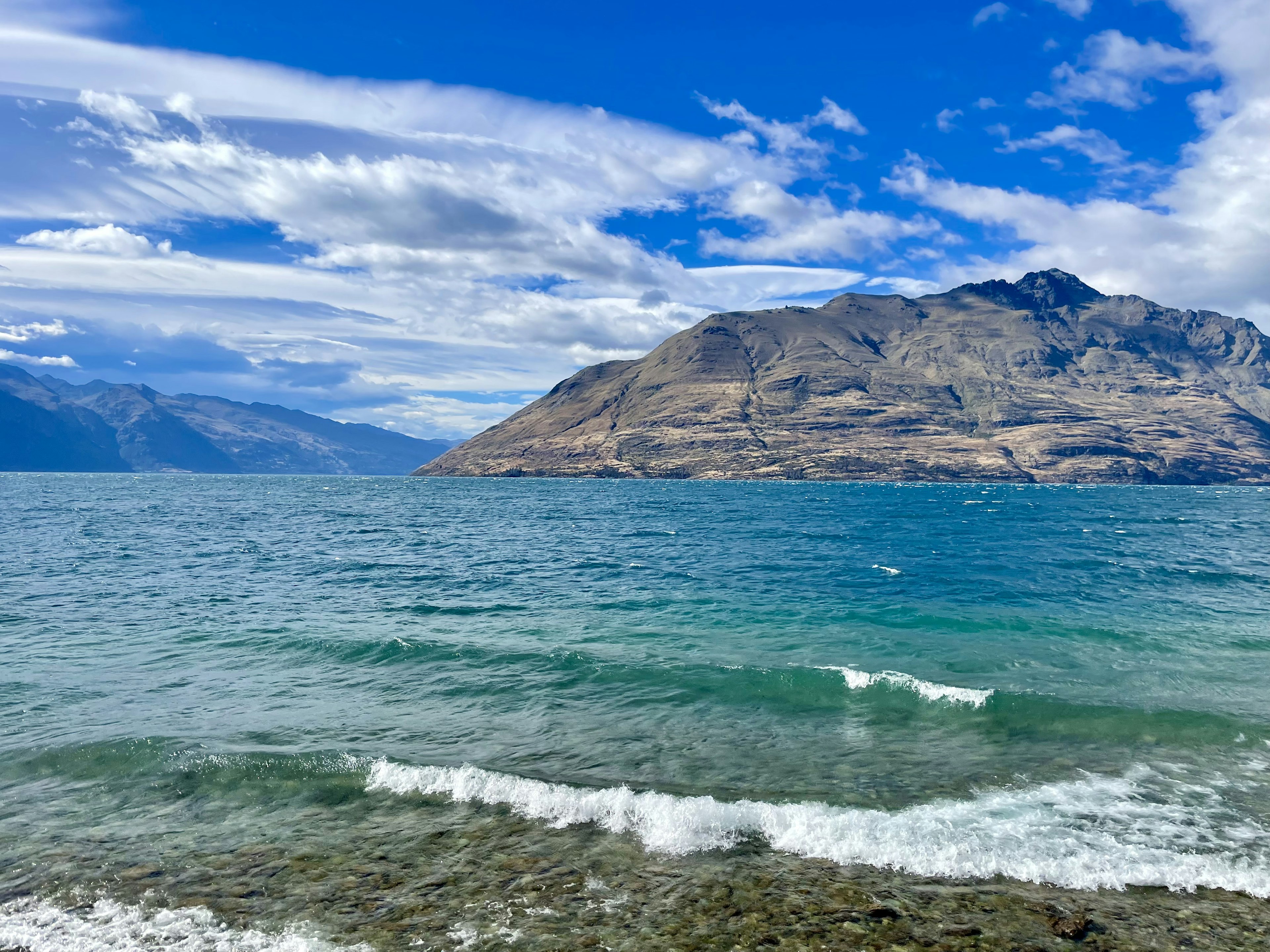 Vista panoramica di mare blu e montagne sotto un cielo nuvoloso