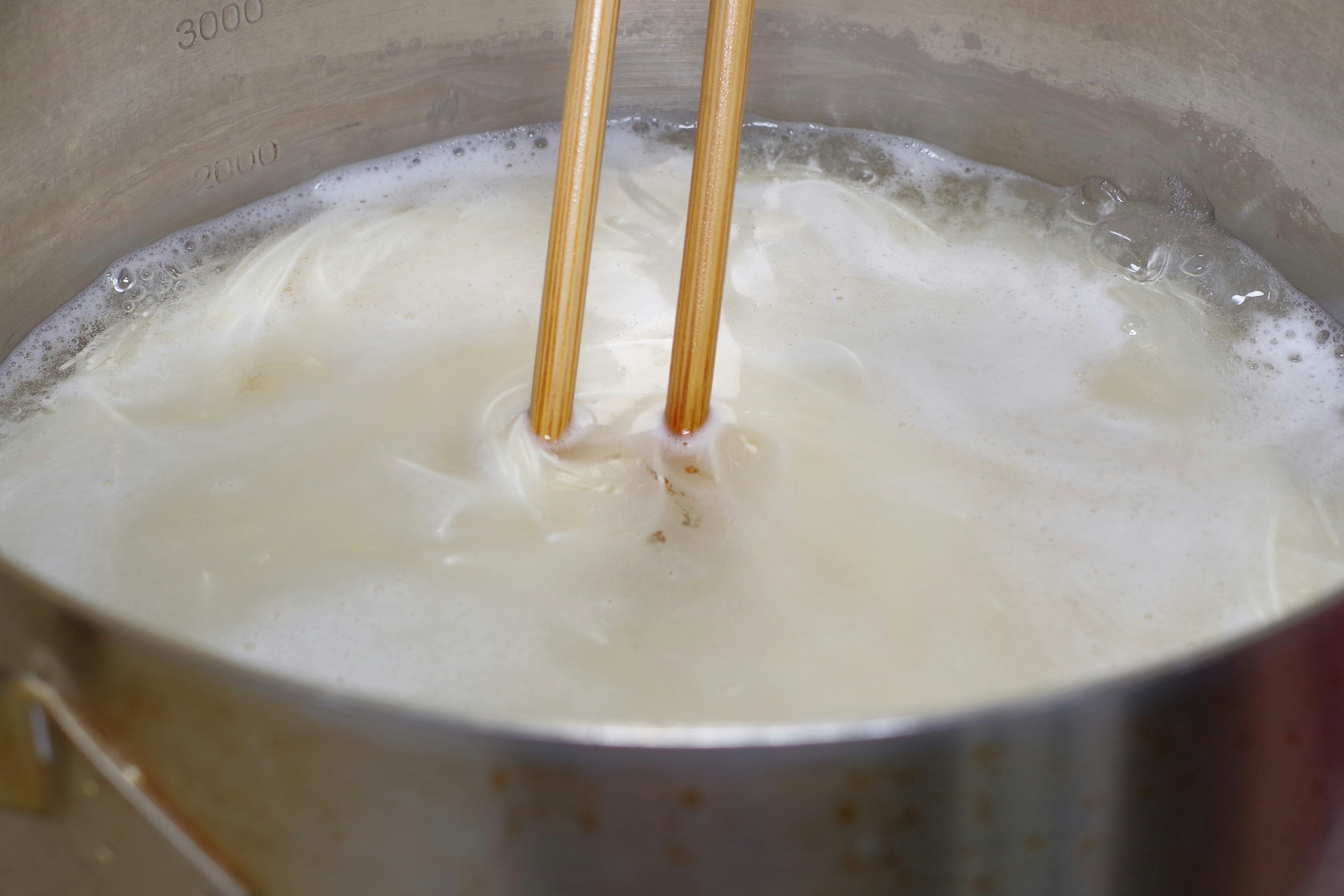 Chopsticks stirring bubbling soup in a pot