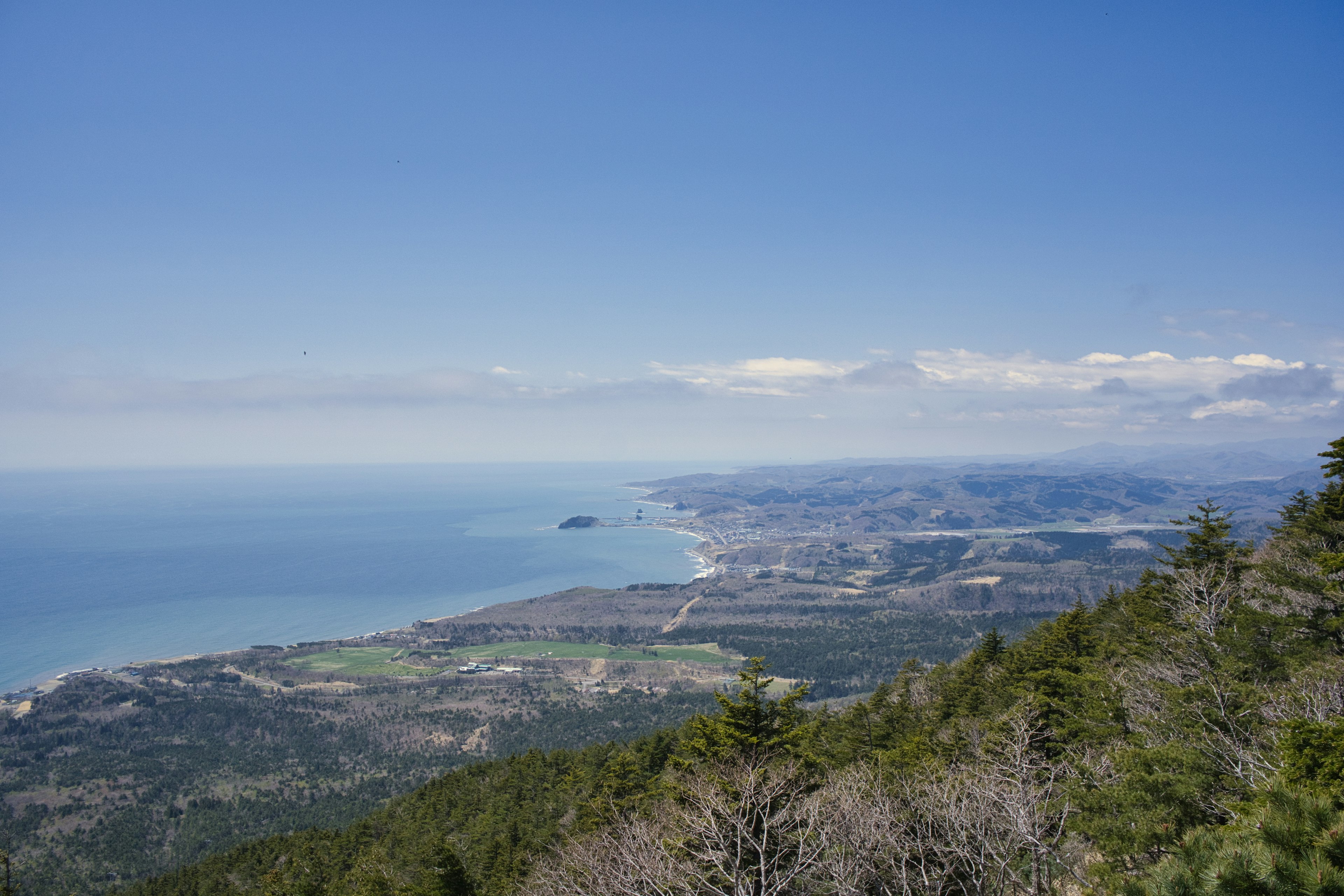 Küstenlandschaft mit Bergen und Ozean unter einem klaren blauen Himmel