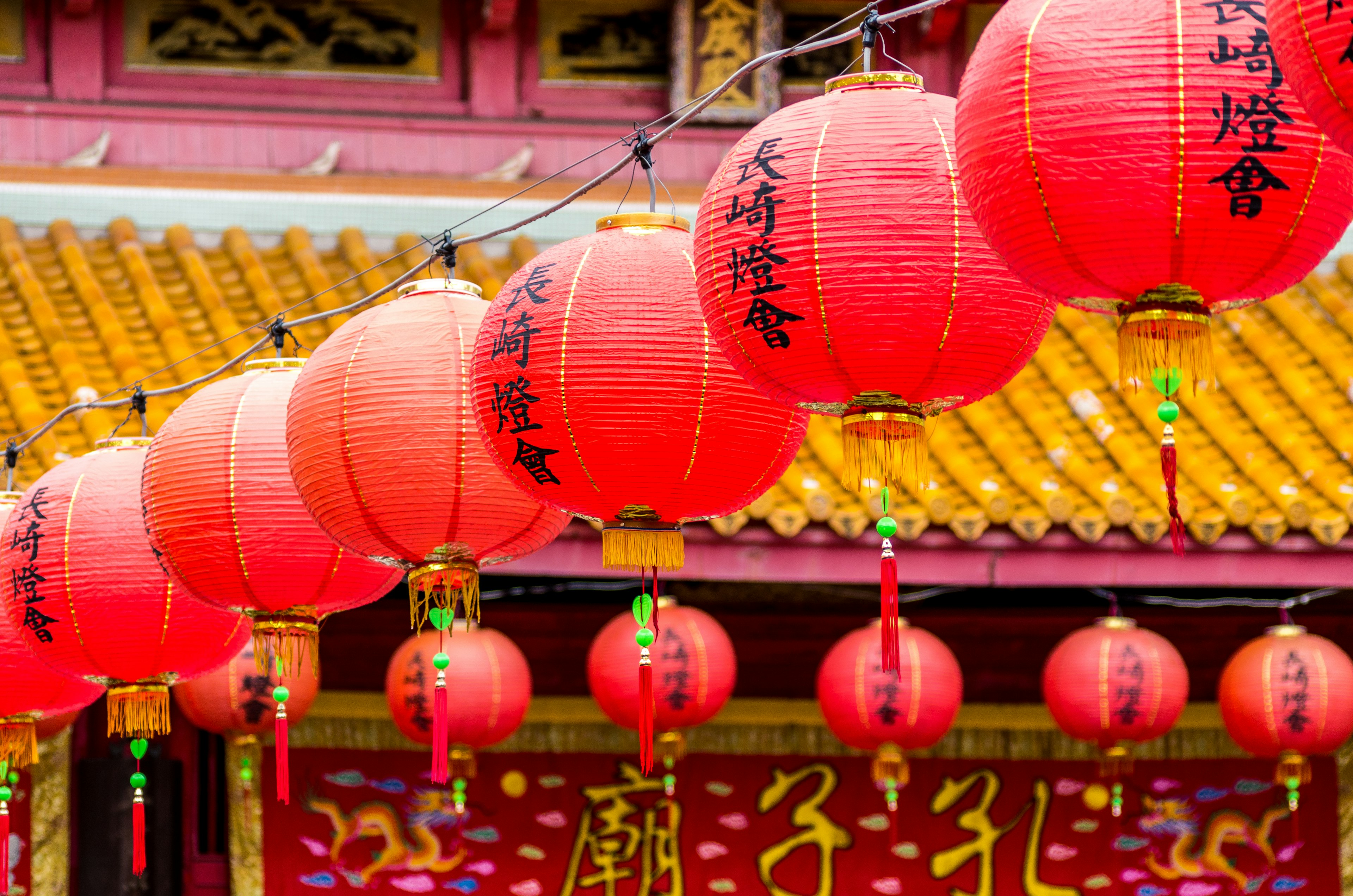 Eine Reihe roter Laternen, die vor einem traditionellen chinesischen Tempel hängen