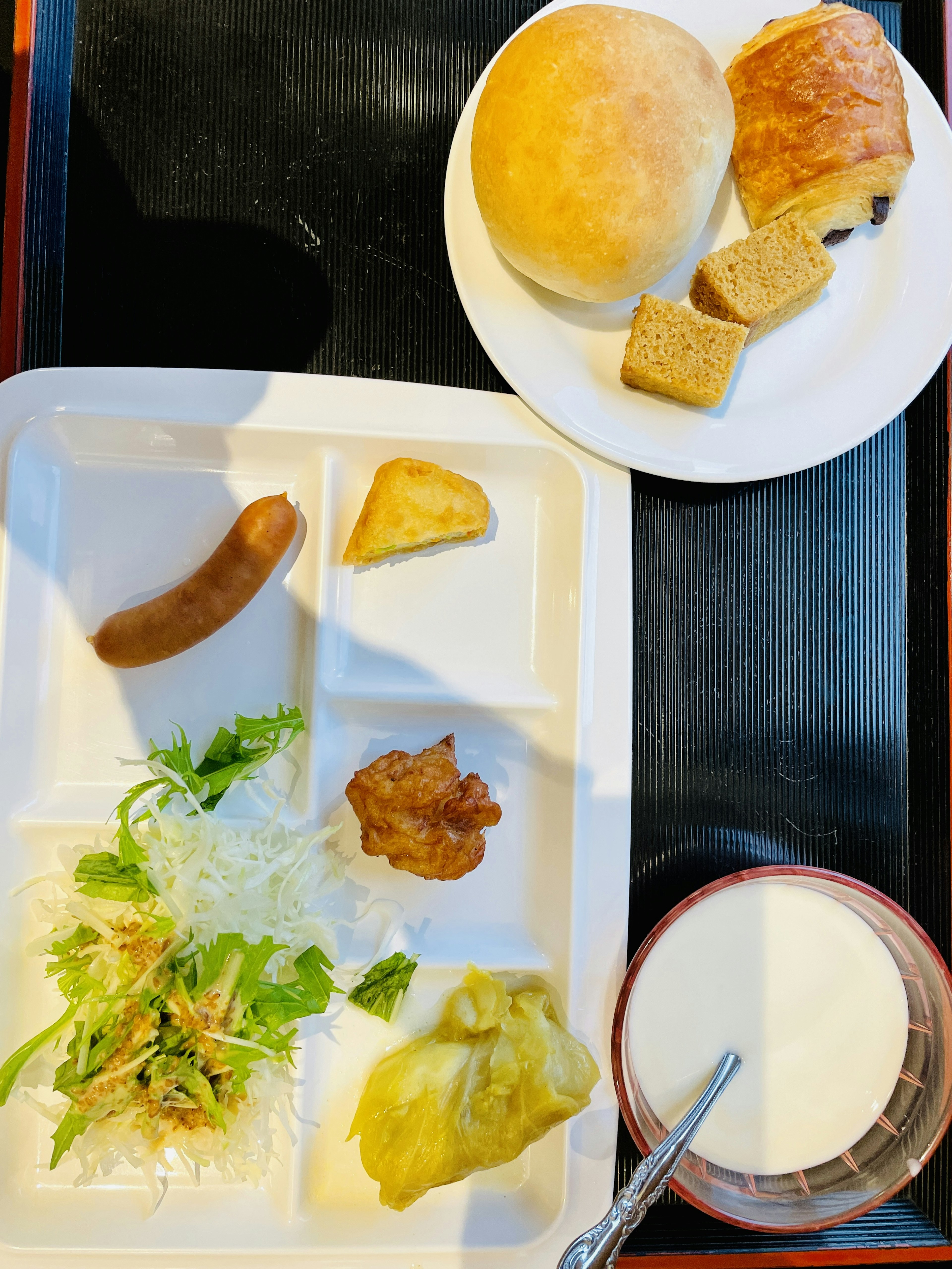 A plate featuring salad, sausage, fried food, cabbage, bread and a glass of milk