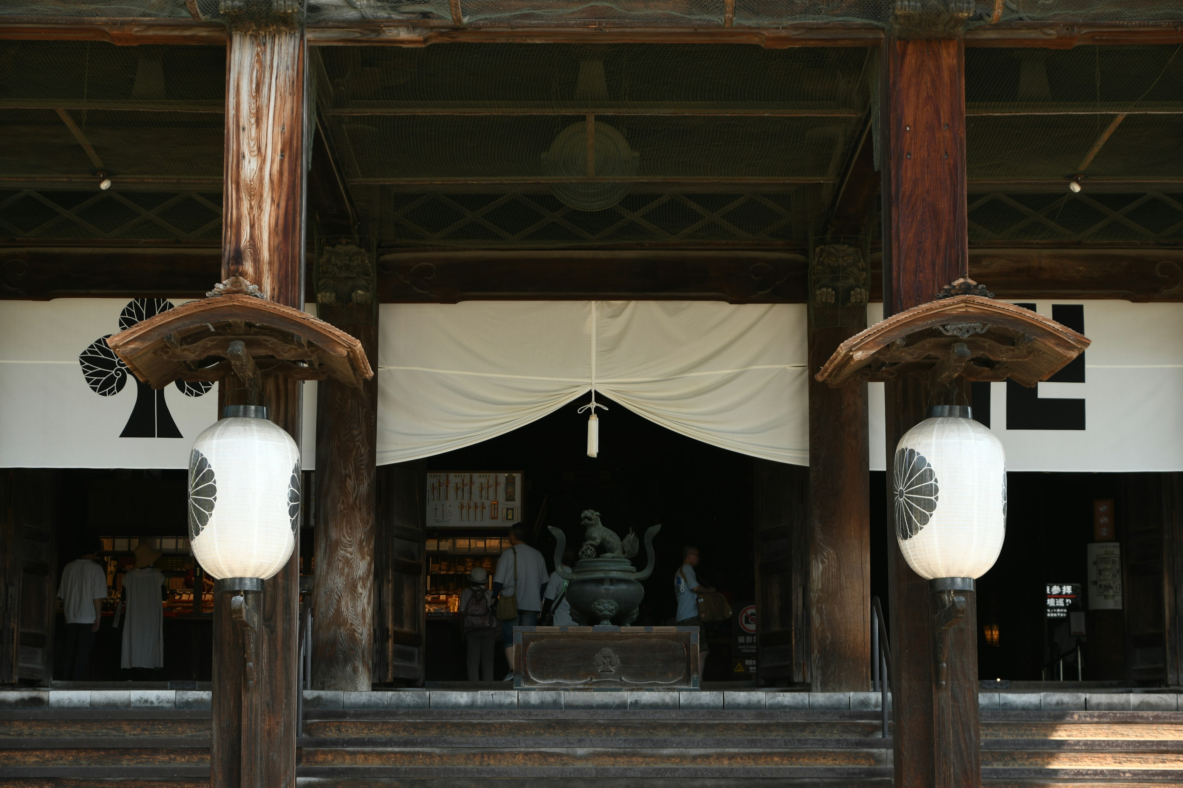 Bâtiment japonais traditionnel avec des piliers en bois et des lanternes au premier plan