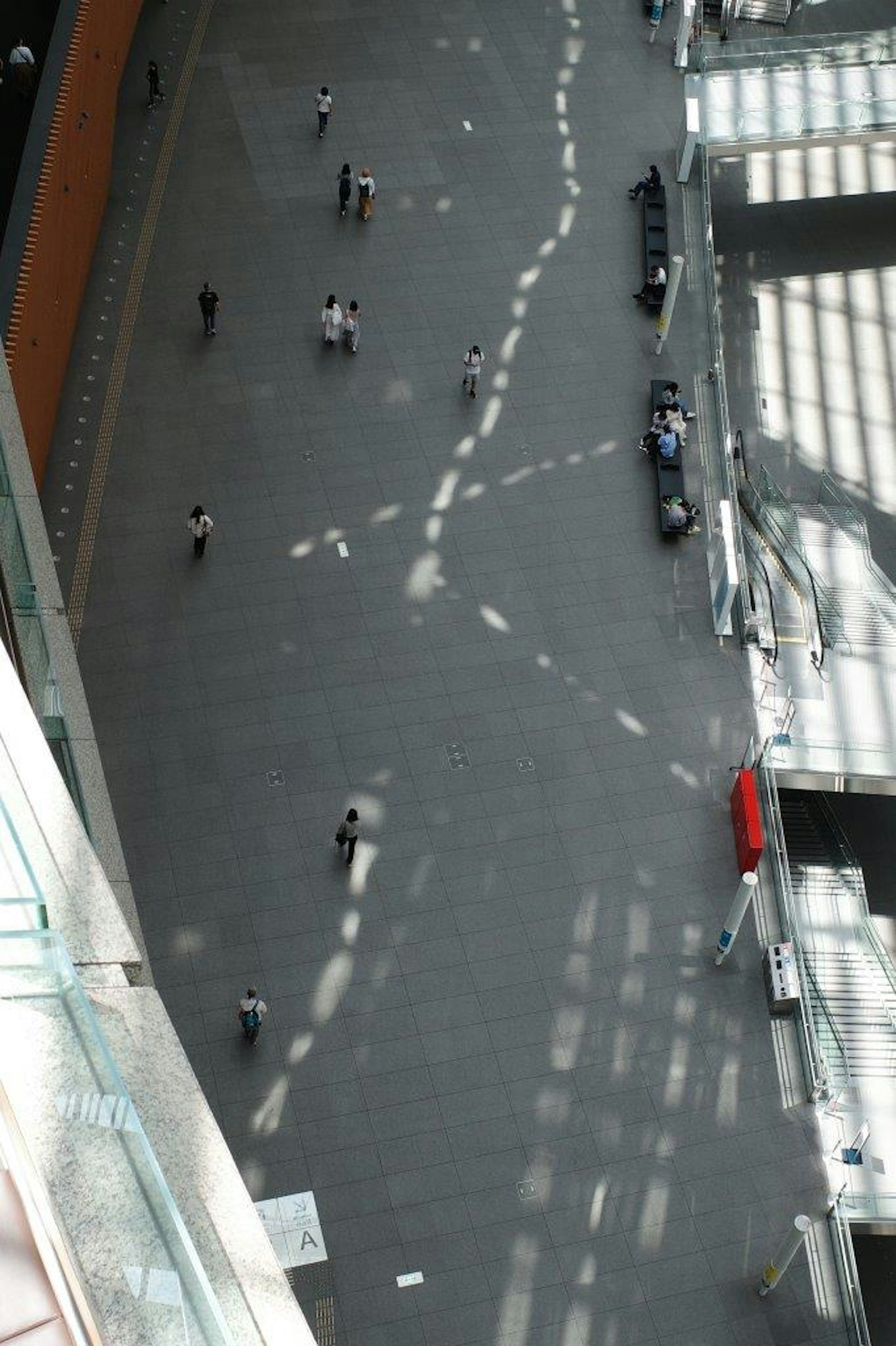 Vista aérea de un amplio interior con personas caminando sobre un suelo decorado