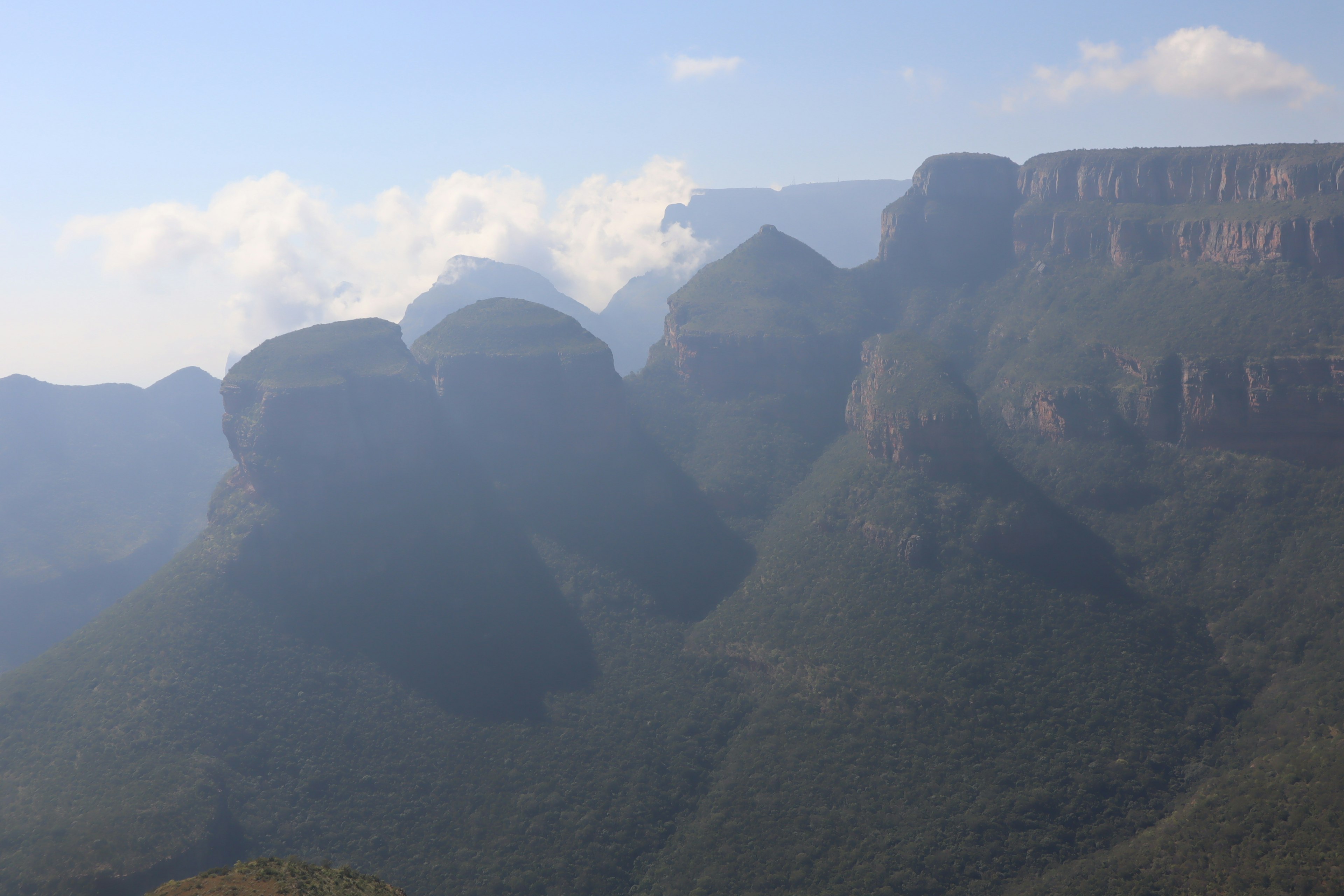 Mountain landscape shrouded in mist with lush green slopes and striking rock formations