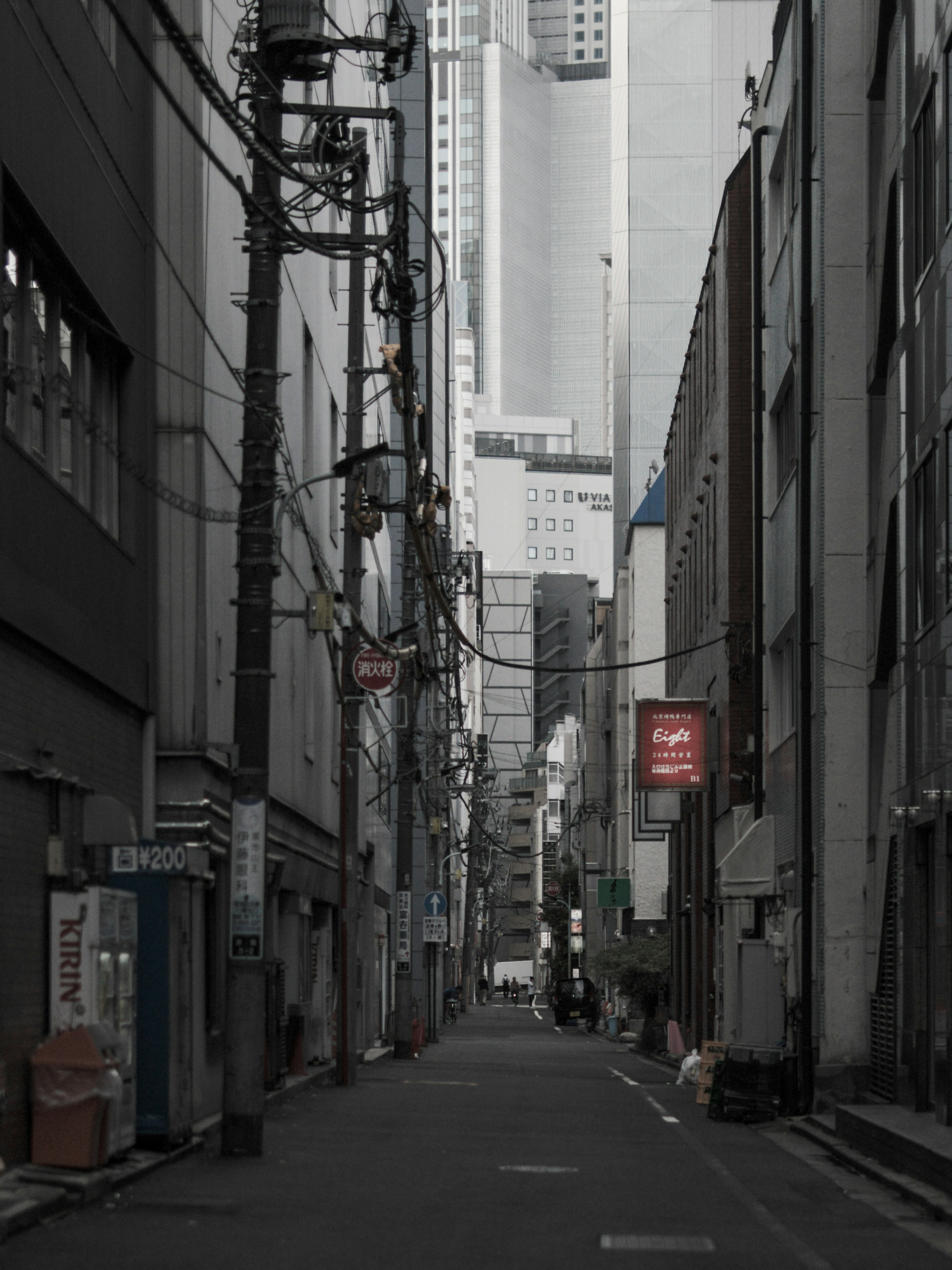 Narrow alleyway surrounded by gray buildings with tangled power lines