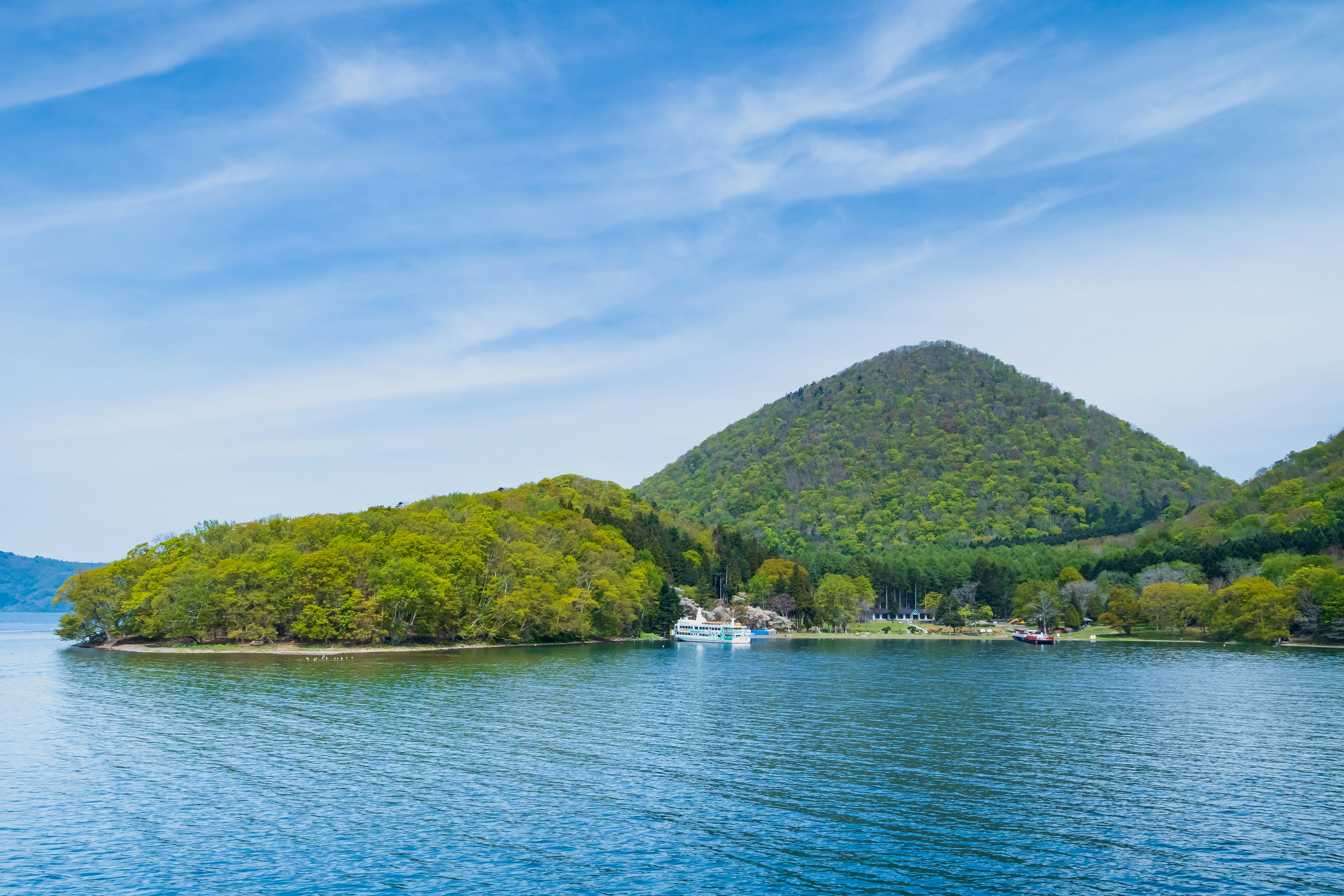 Vista panoramica di un cielo blu e acqua con un'isola verde e una montagna