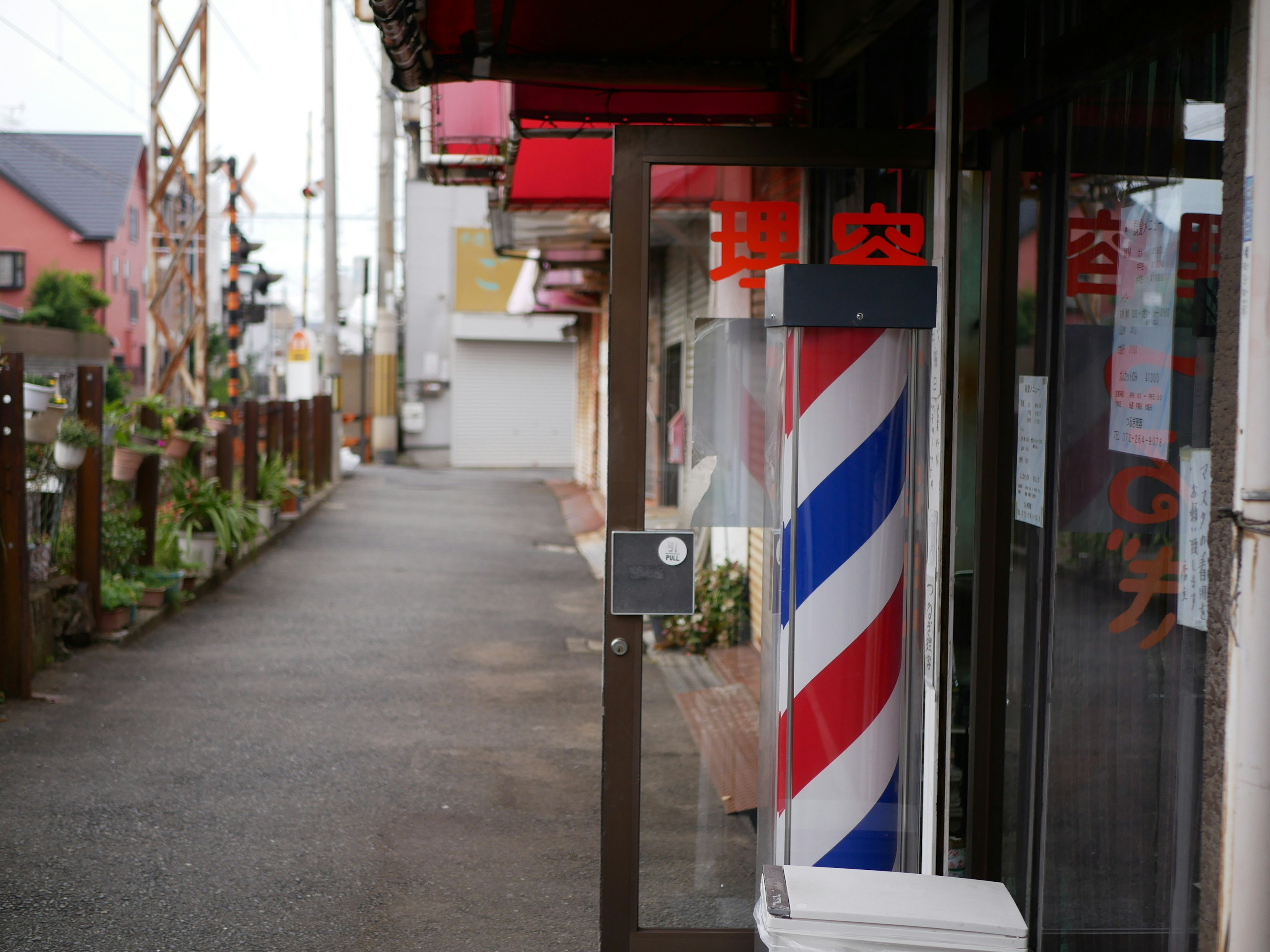 Exterior de barbería con un poste de barbero a rayas rojas y azules