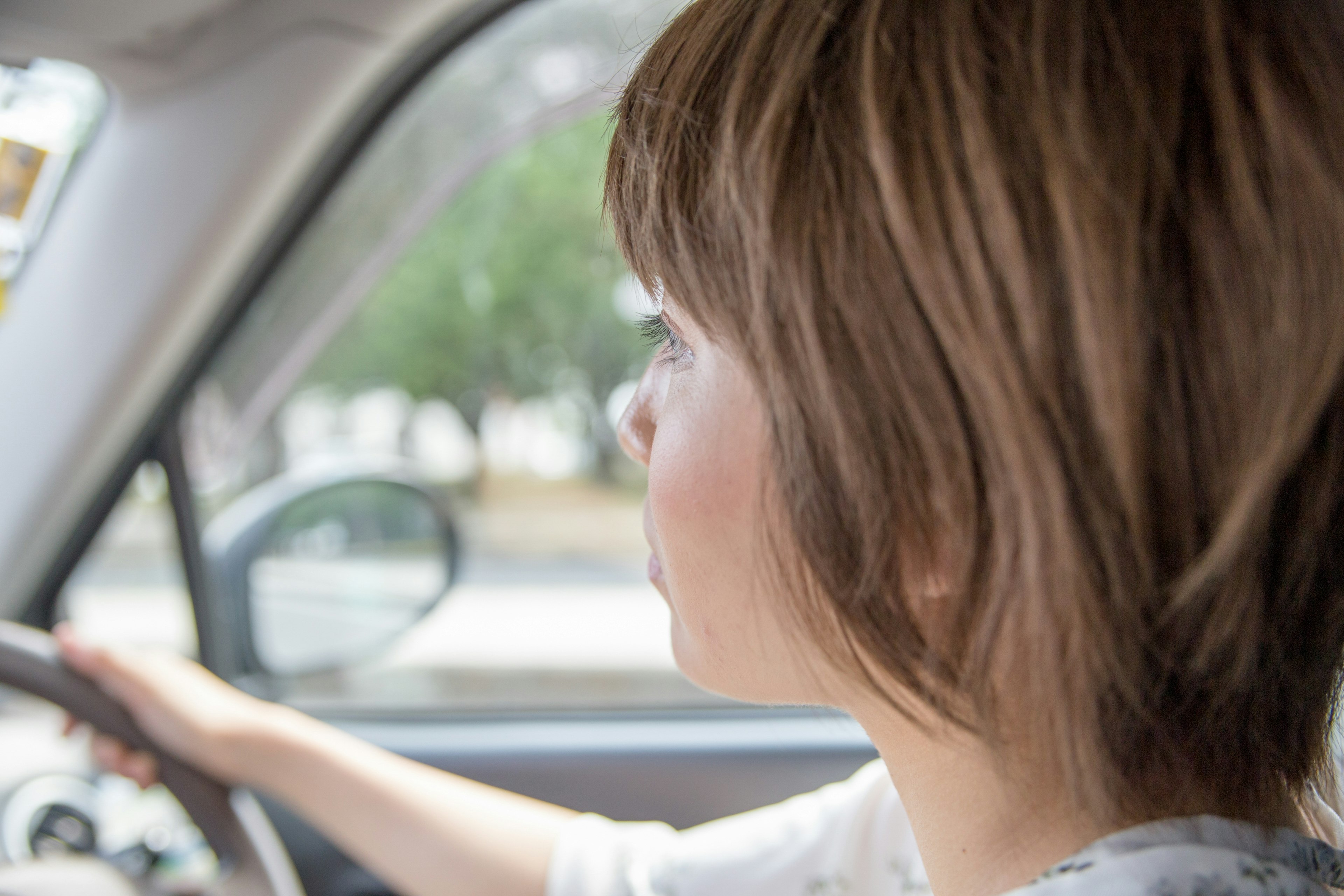 Profile of a young woman driving a car interior visible