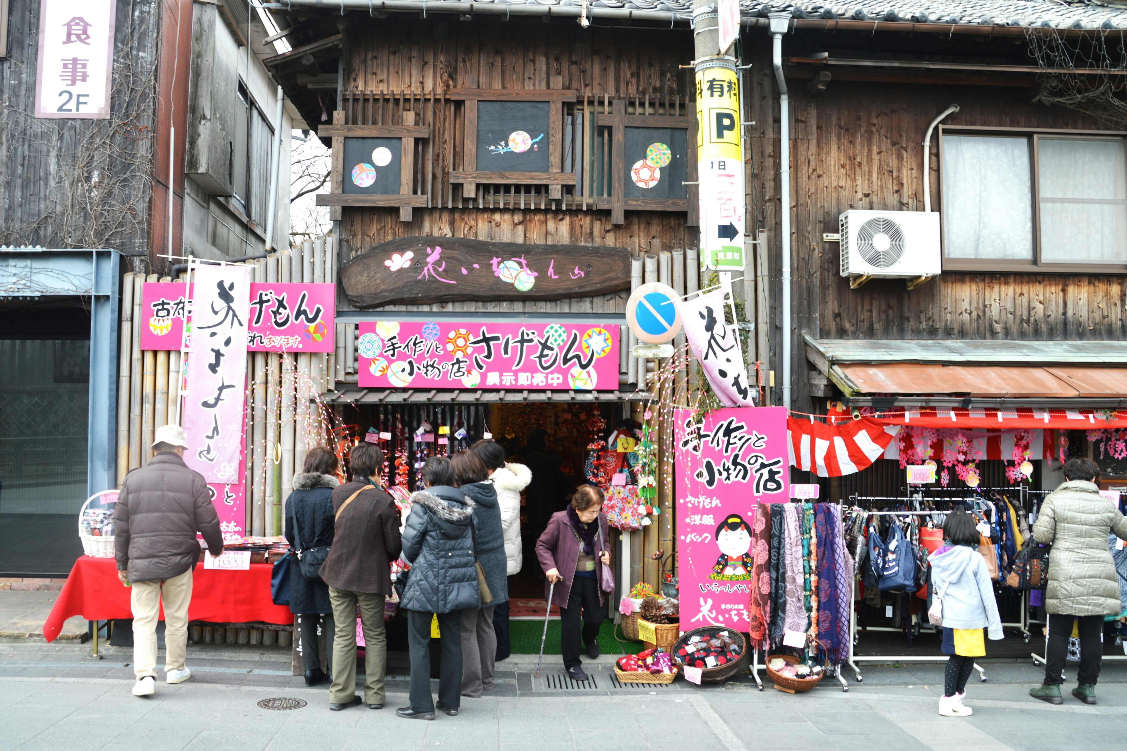 Magasin en bois traditionnel avec des gens rassemblés devant Signe rose et présentations de produits colorés