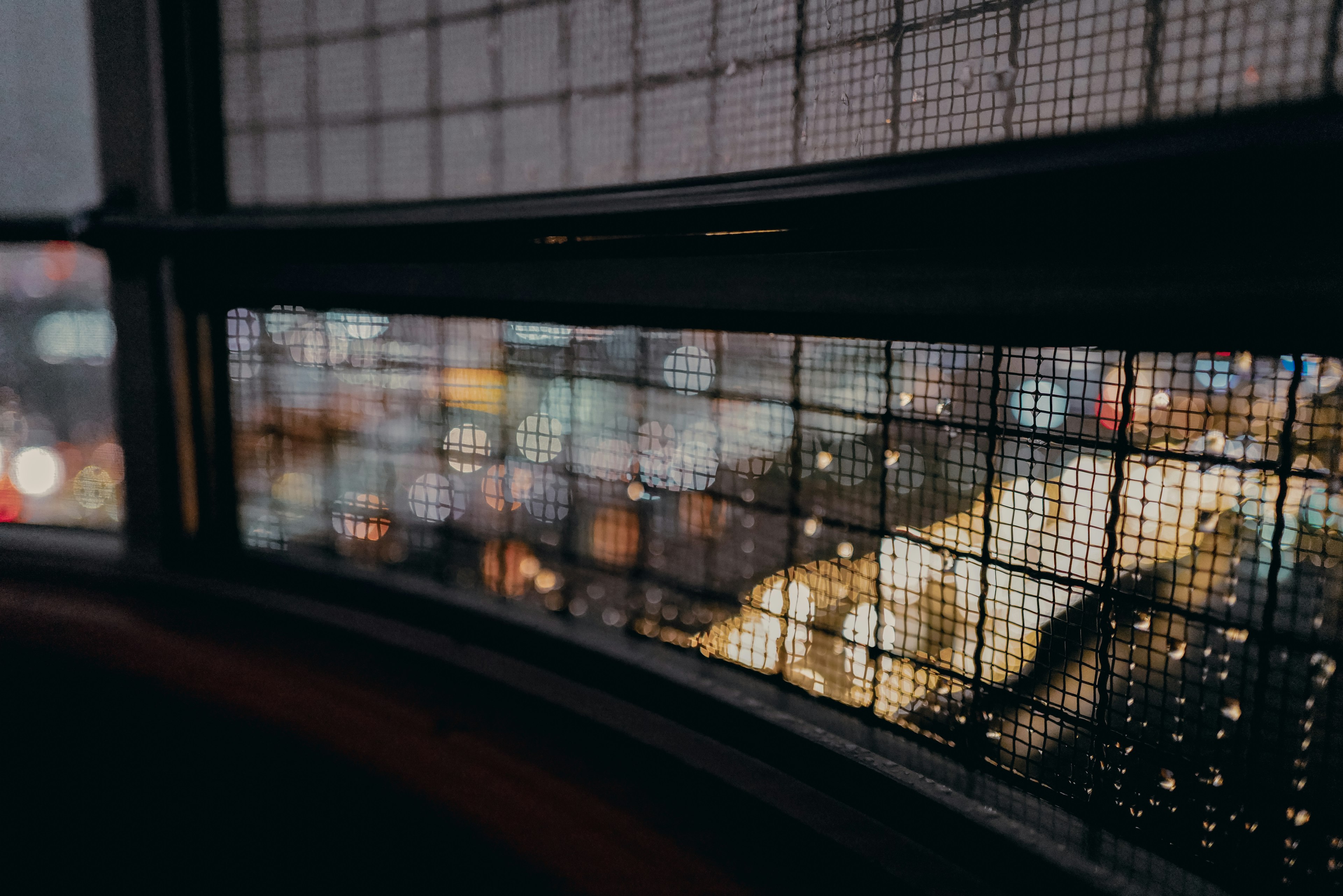 Stadtansicht bei Nacht durch ein Gitterfenster