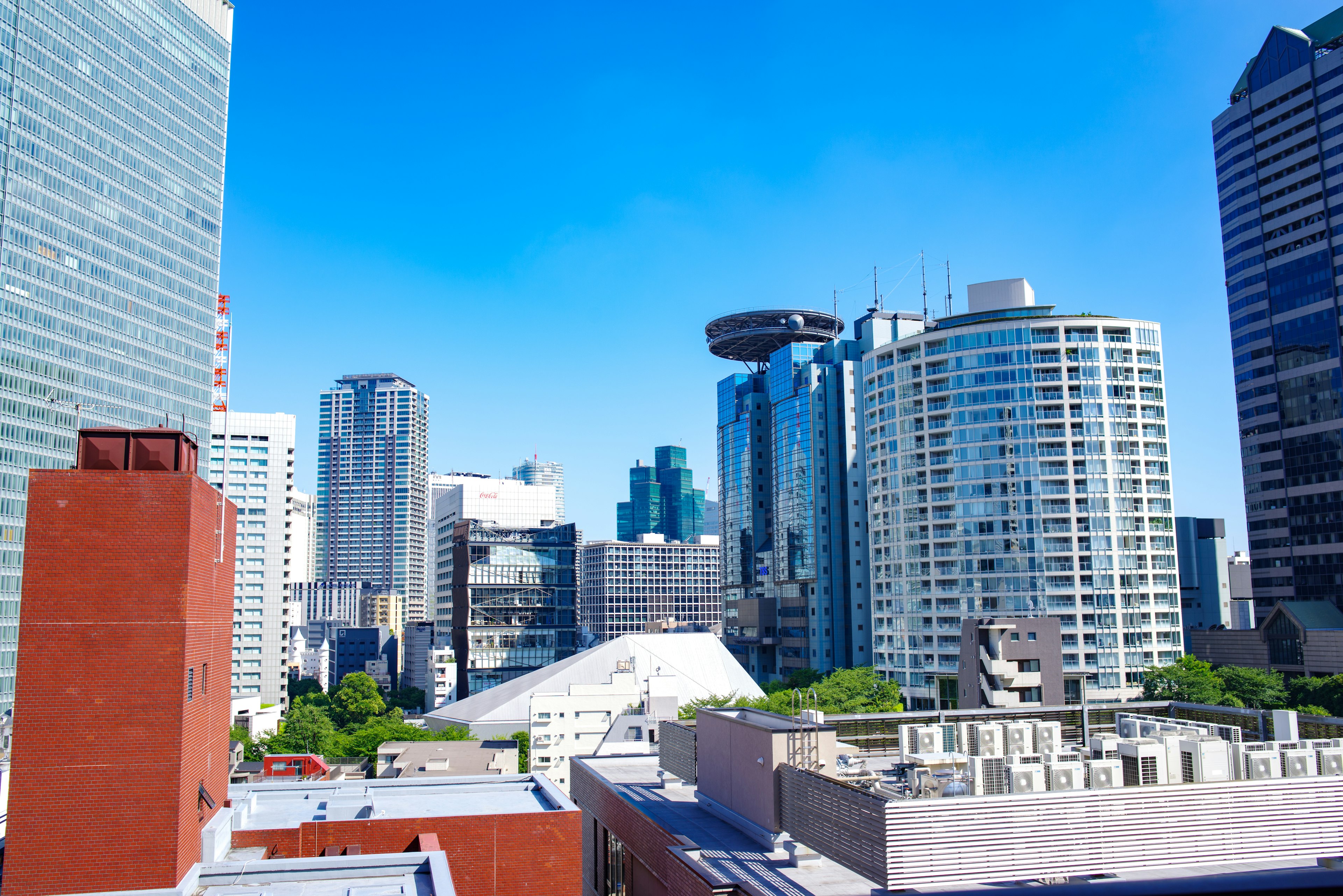 Skyline moderna de la ciudad bajo un cielo azul brillante con edificios altos y árboles verdes