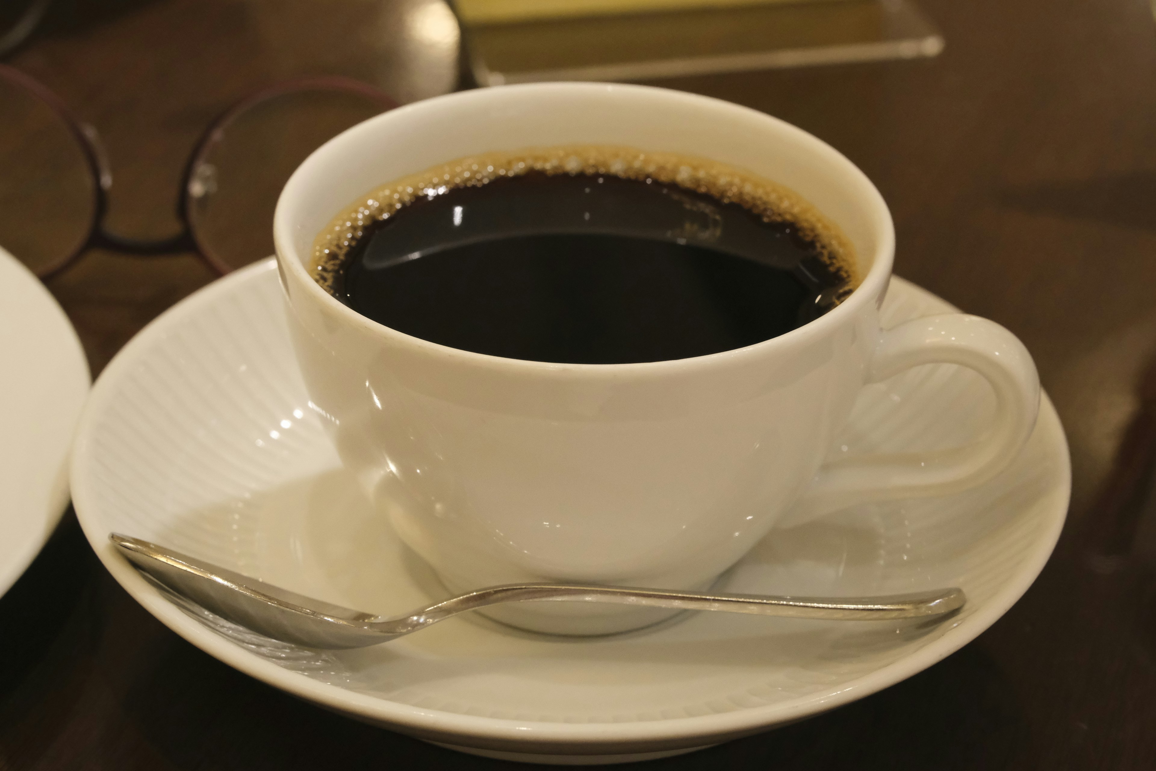 Café negro en una taza blanca con una cuchara