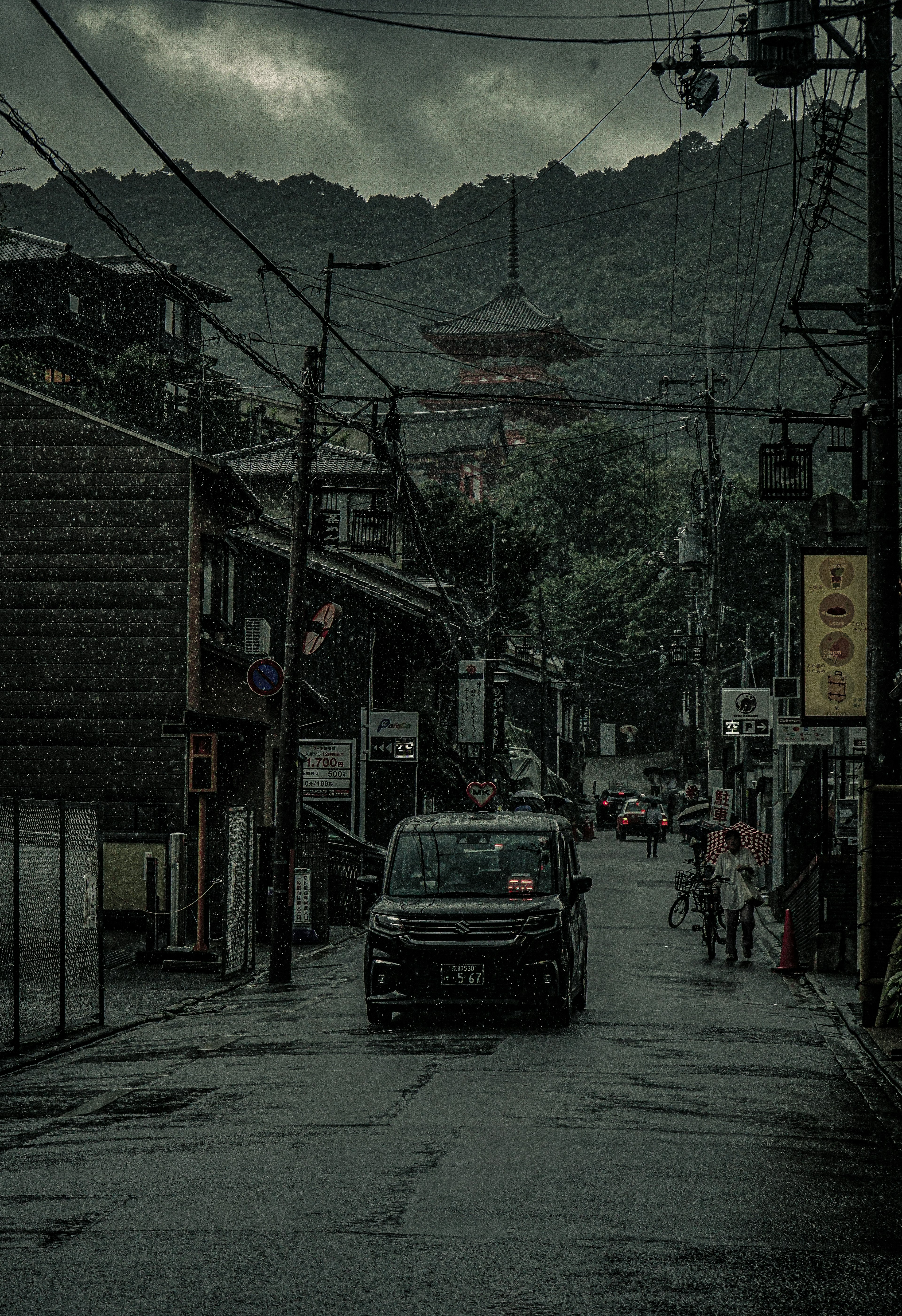 暗い雲に覆われた街並みの中を走る車と古い建物