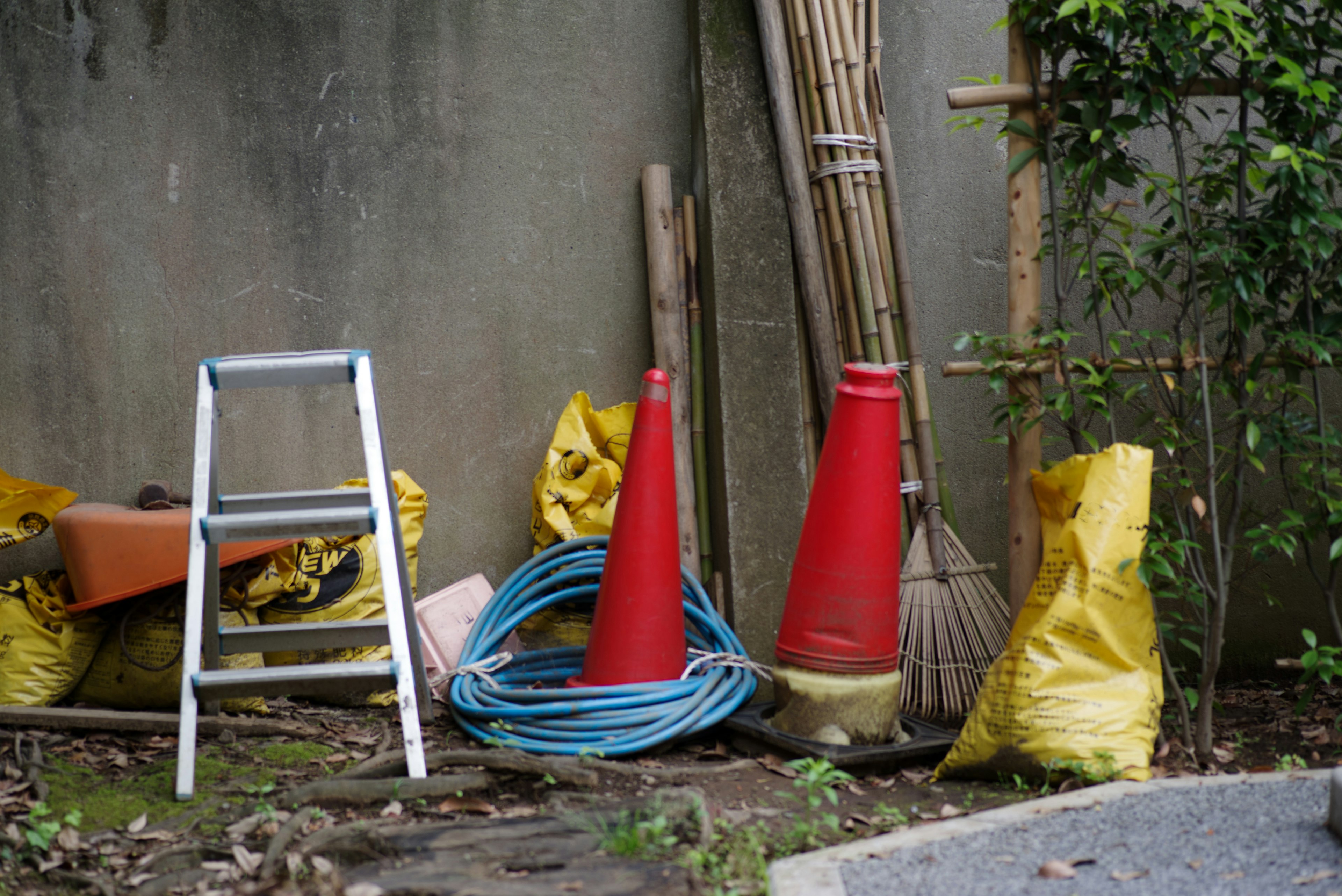 A corner of a yard featuring red cones and yellow bags with cleaning tools