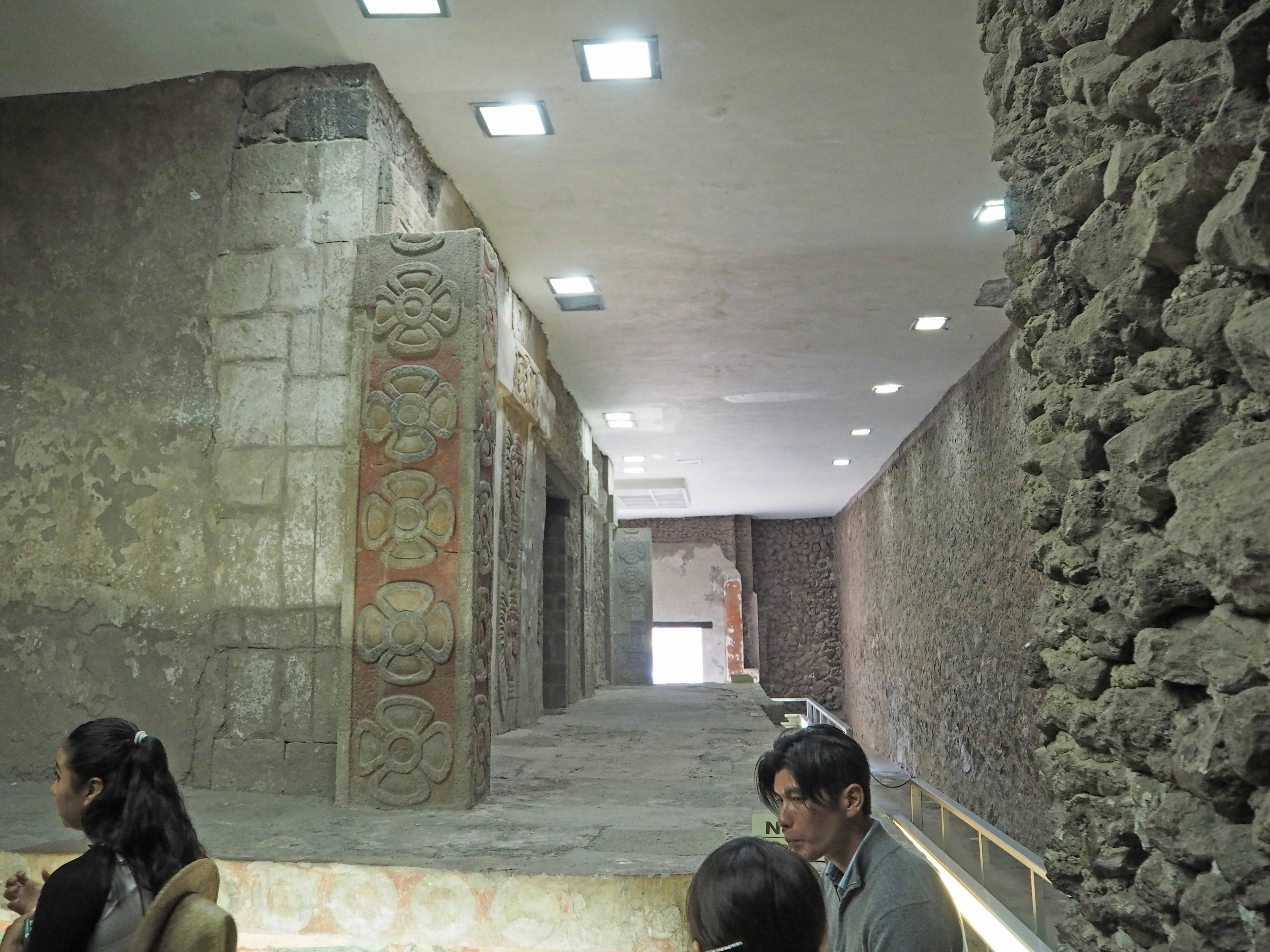 Interior de una sala de exposición histórica con murales antiguos y esculturas de piedra