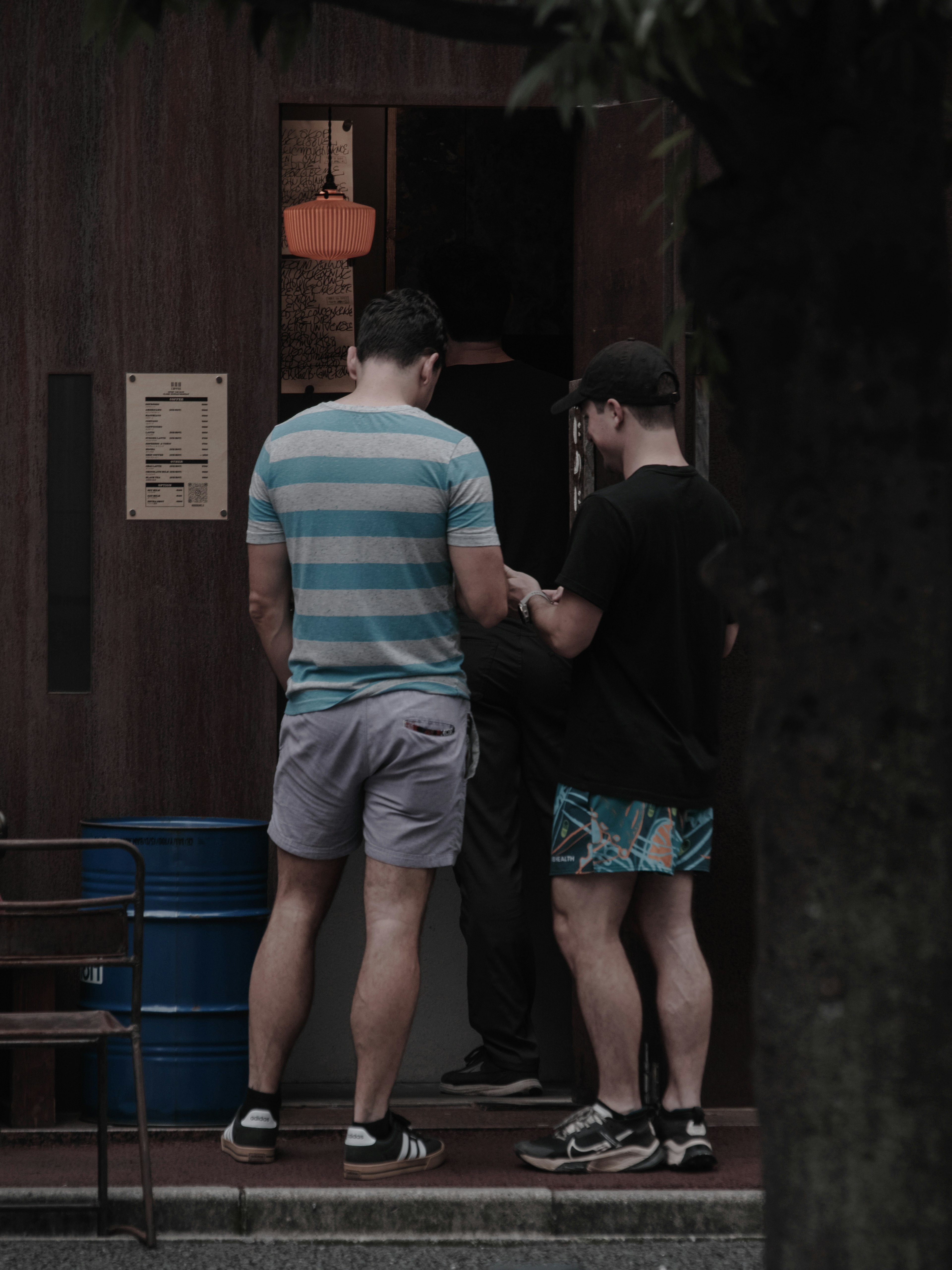 Two men in casual attire talking outside a building with trees in the background