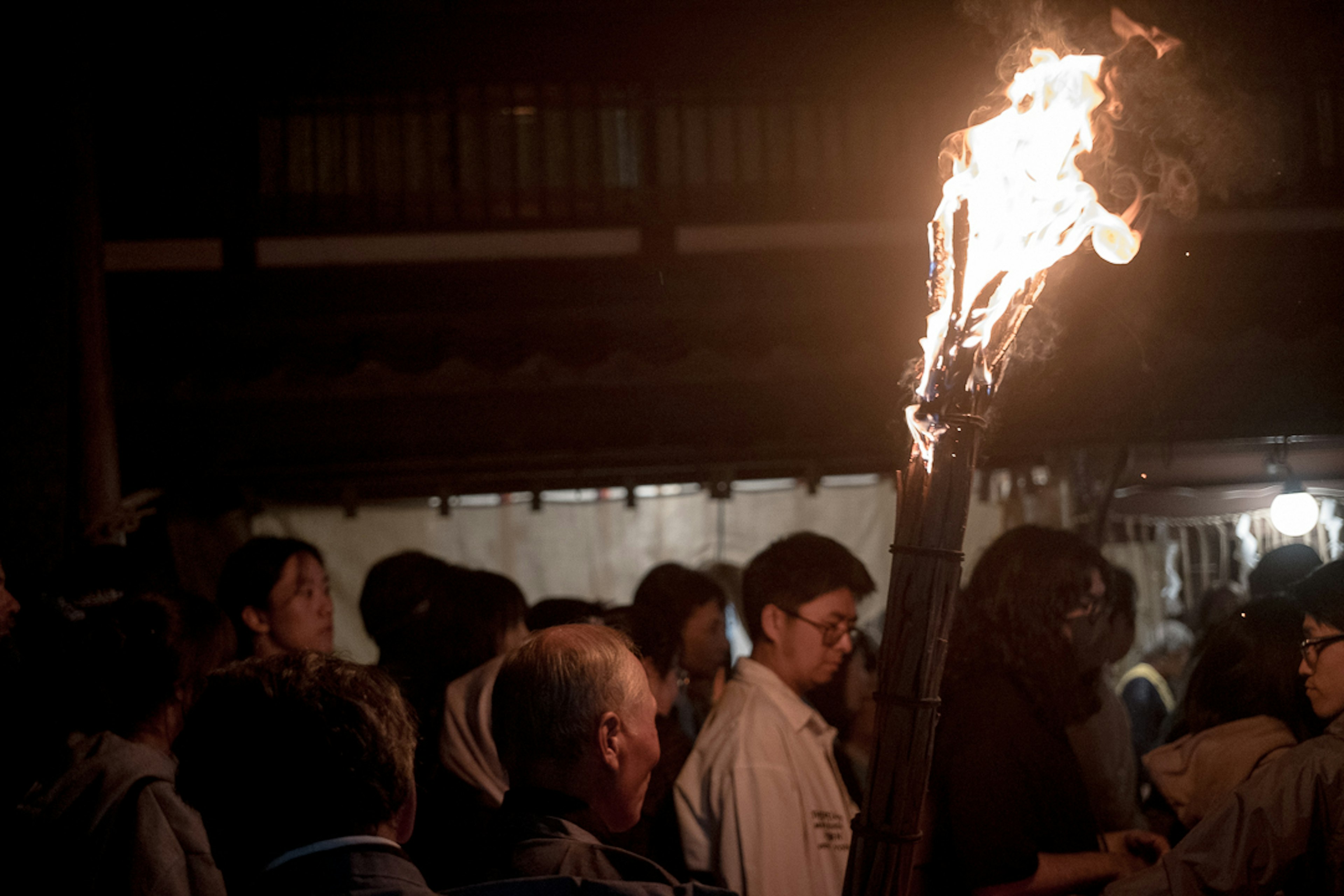 Une personne tenant un flambeau enflammé dans une foule sombre