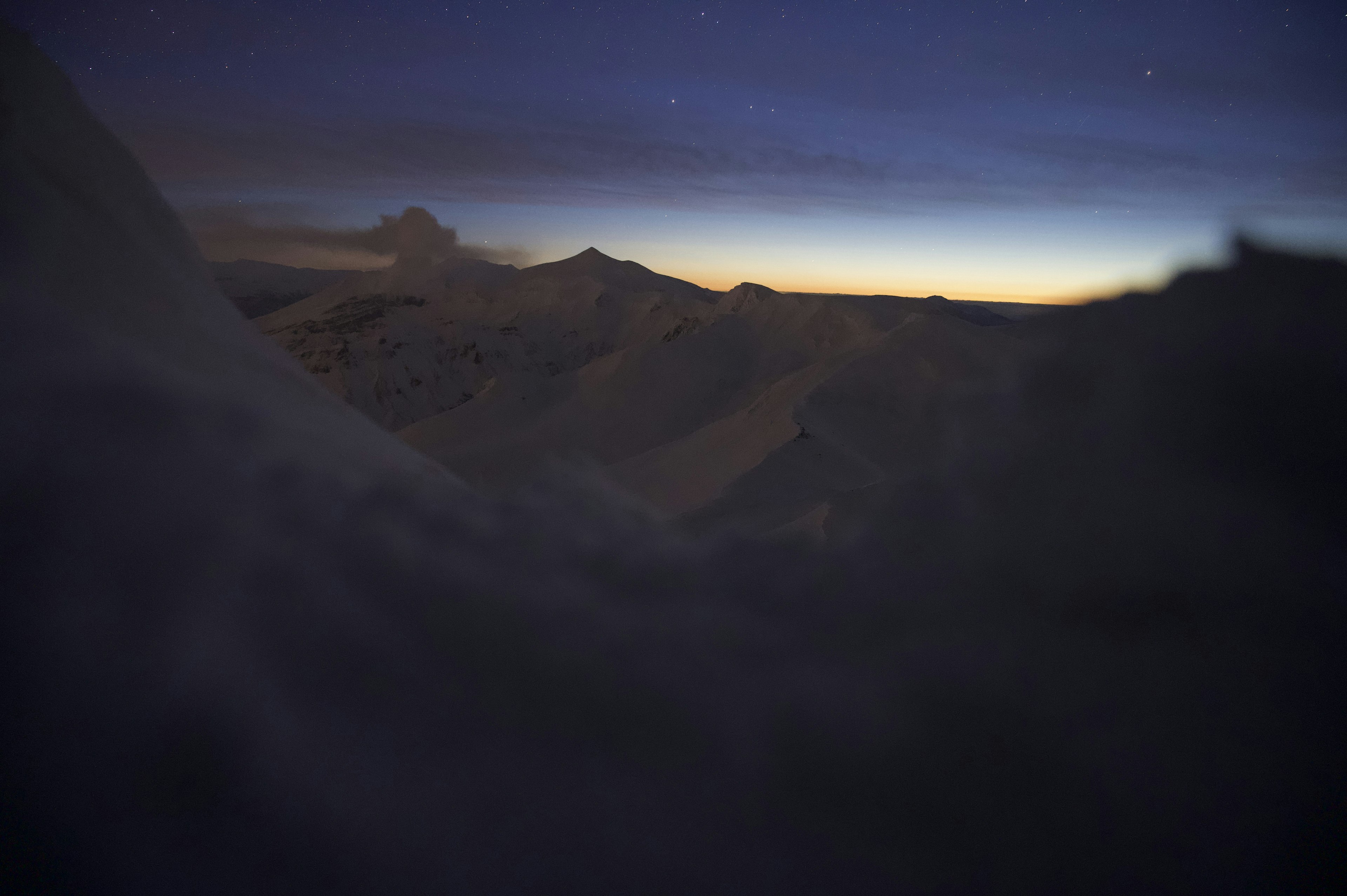 Terreno innevato con un paesaggio montano al crepuscolo