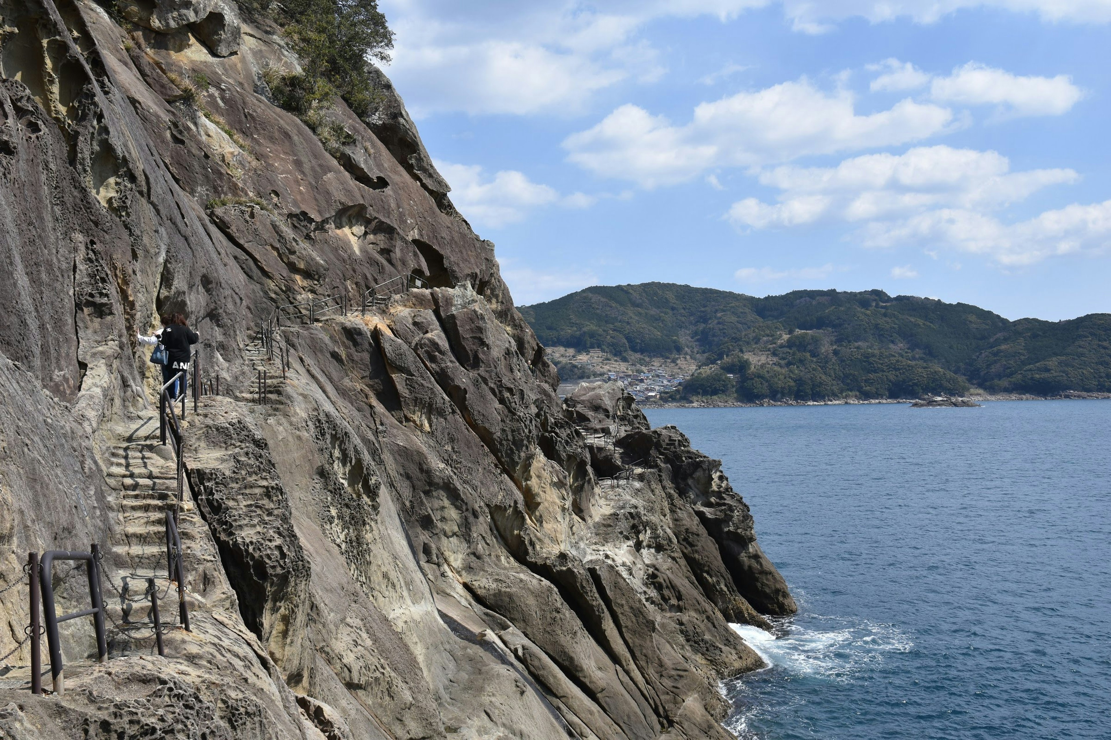 海岸の岩壁に沿った小道と青い海の景色