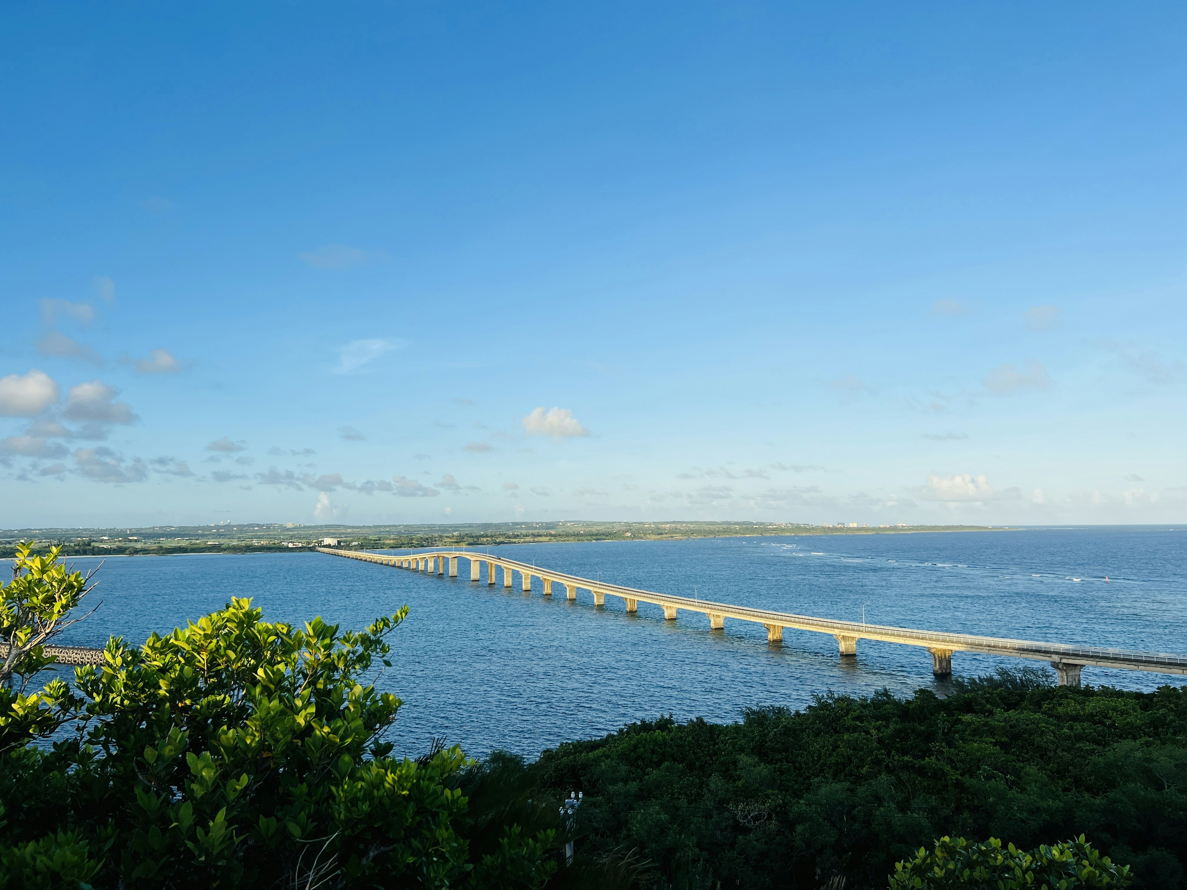 Long bridge stretching over the ocean under a clear blue sky