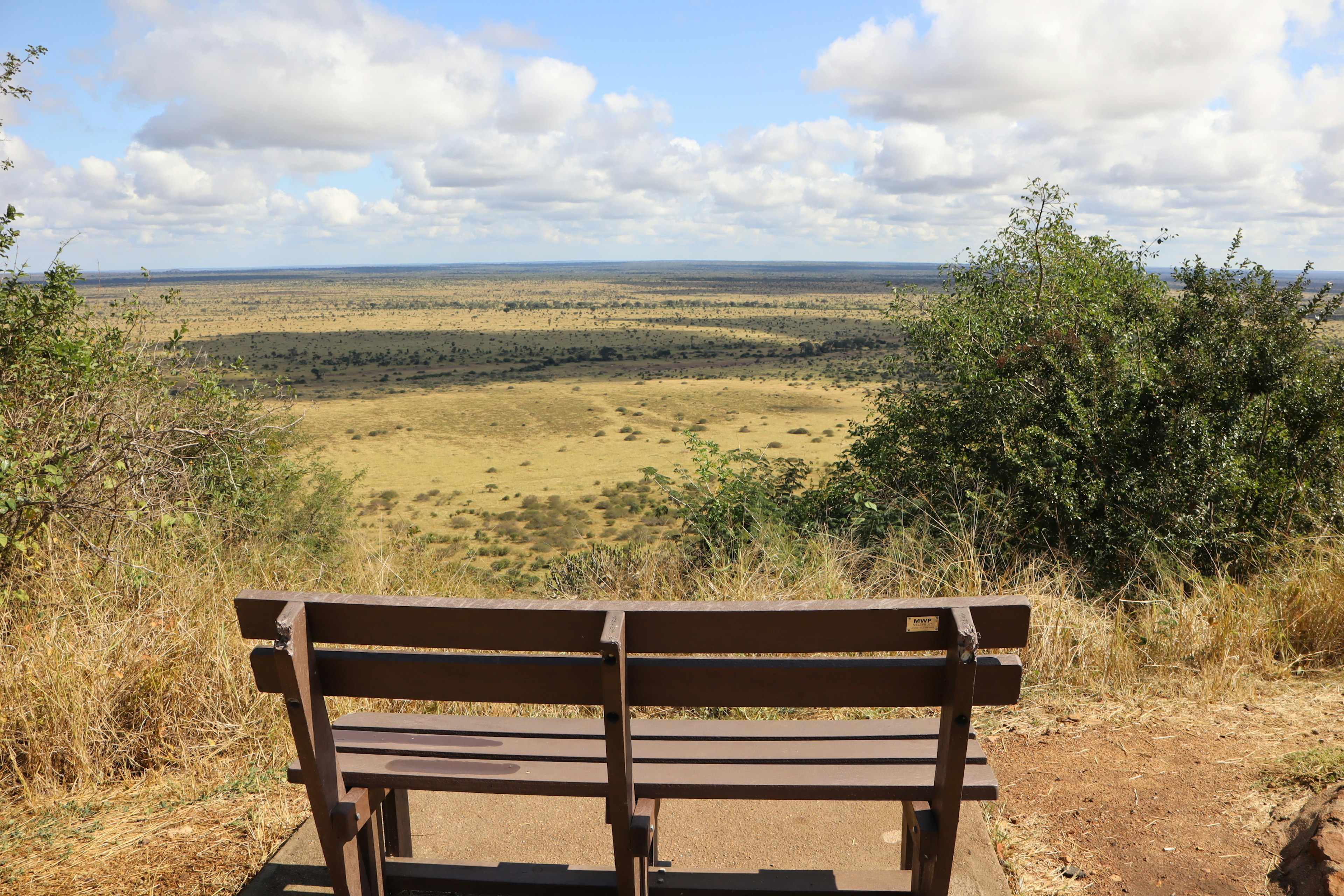 A bench overlooking a vast grassland and blue sky