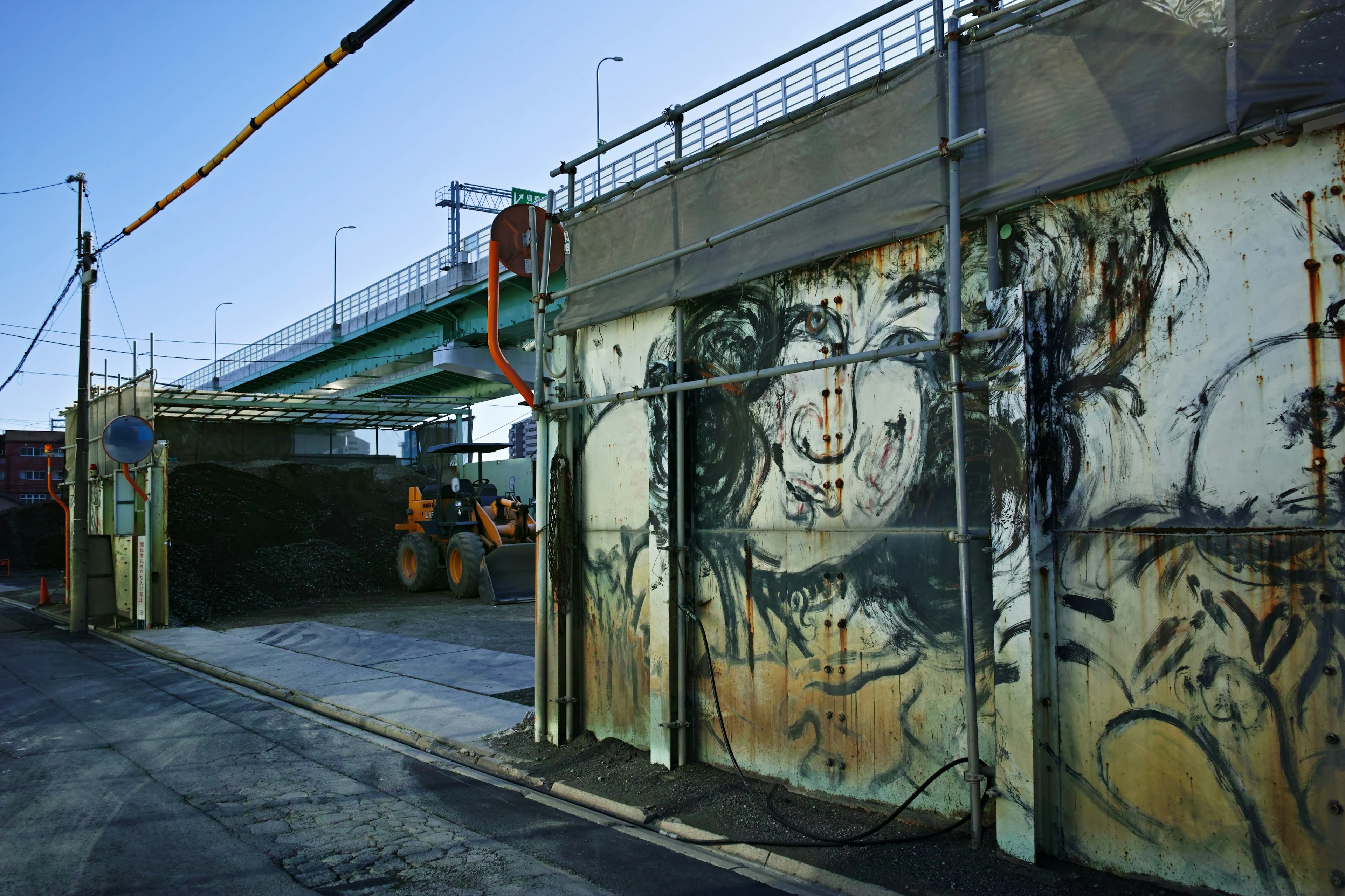 Kunst an einer Baustellenwand mit einer nahegelegenen Brücke