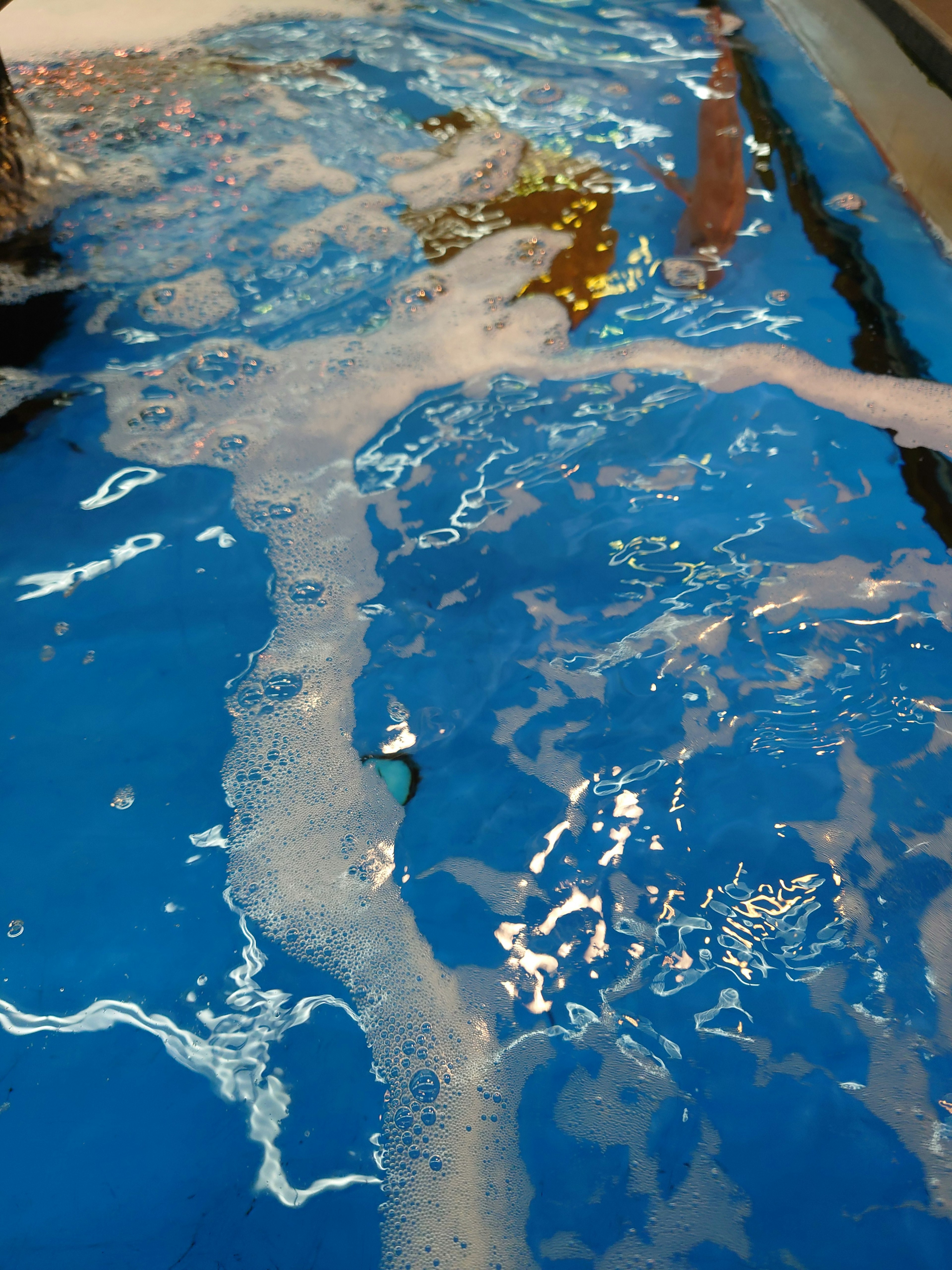 Surface d'eau bleue avec des bulles et une main submergée