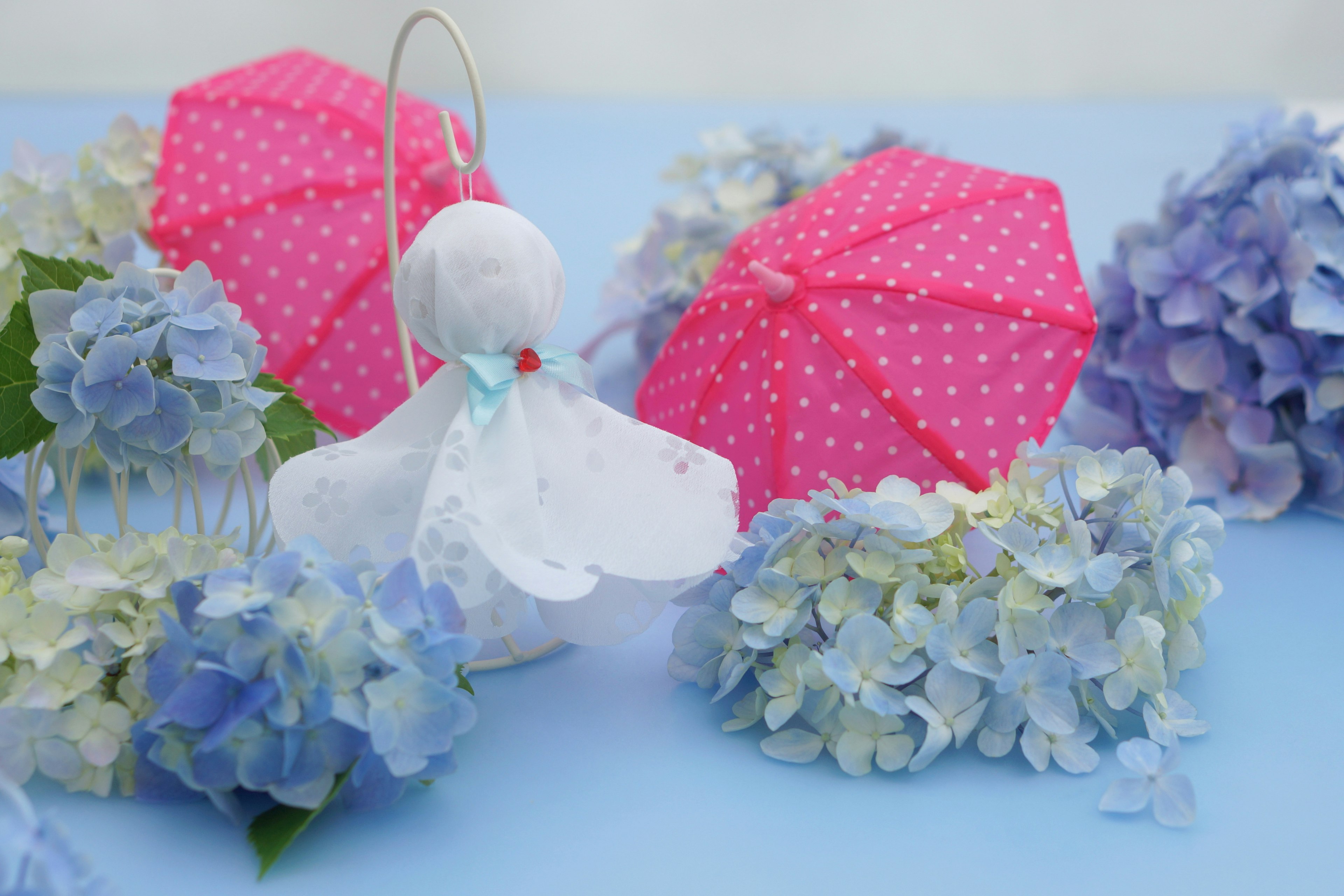 Eine charmante Szene mit rosa Regenschirmen und blauen Hortensien auf blauem Hintergrund