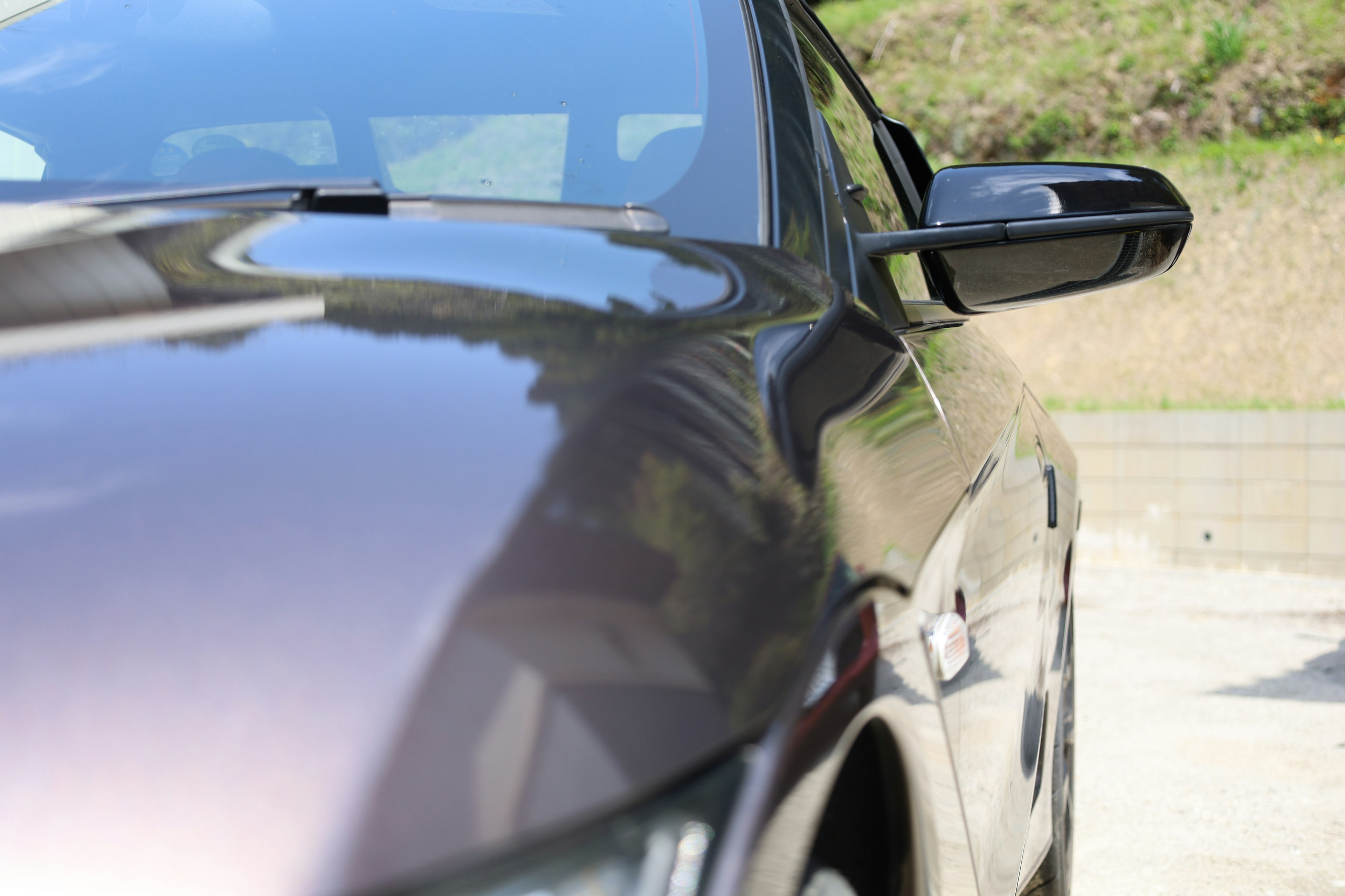 Close-up bodi mobil coklat mengkilap dengan spion samping terlihat